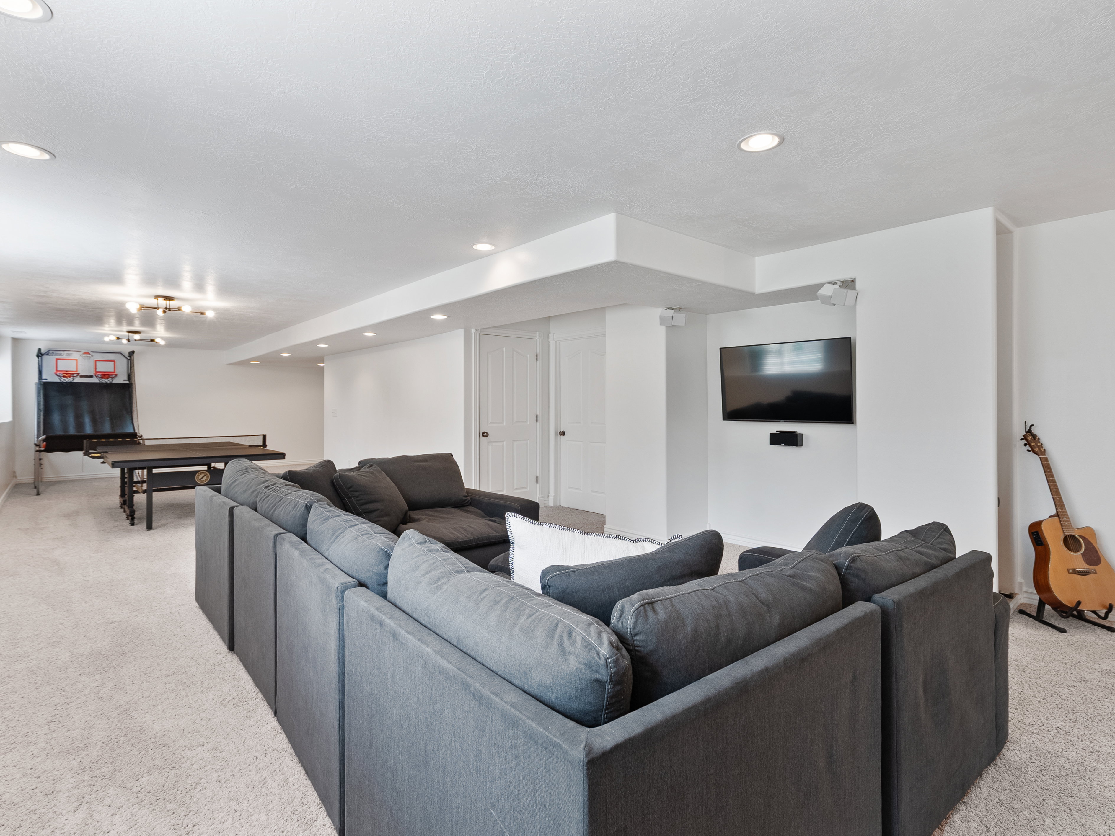 Spacious recreation area featuring recessed lighting, light-colored carpeting, white walls, and a built-in entertainment setup