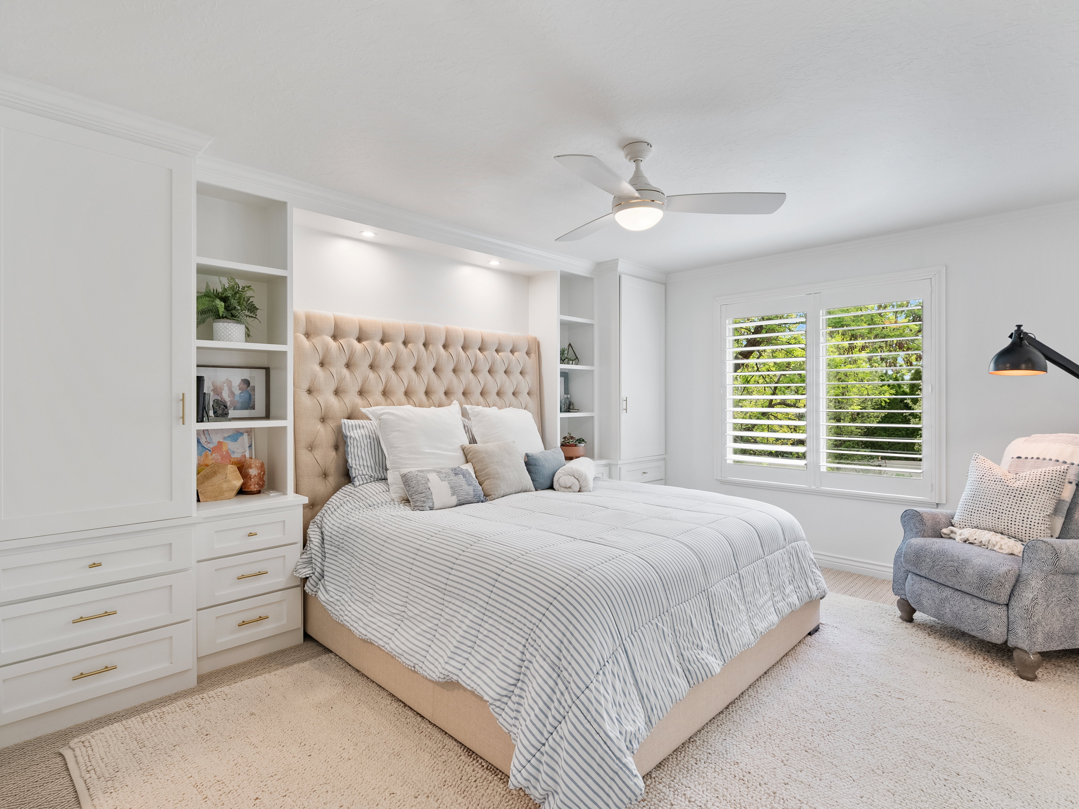Built-in cabinetry with integrated shelving and drawers flanks a tufted headboard