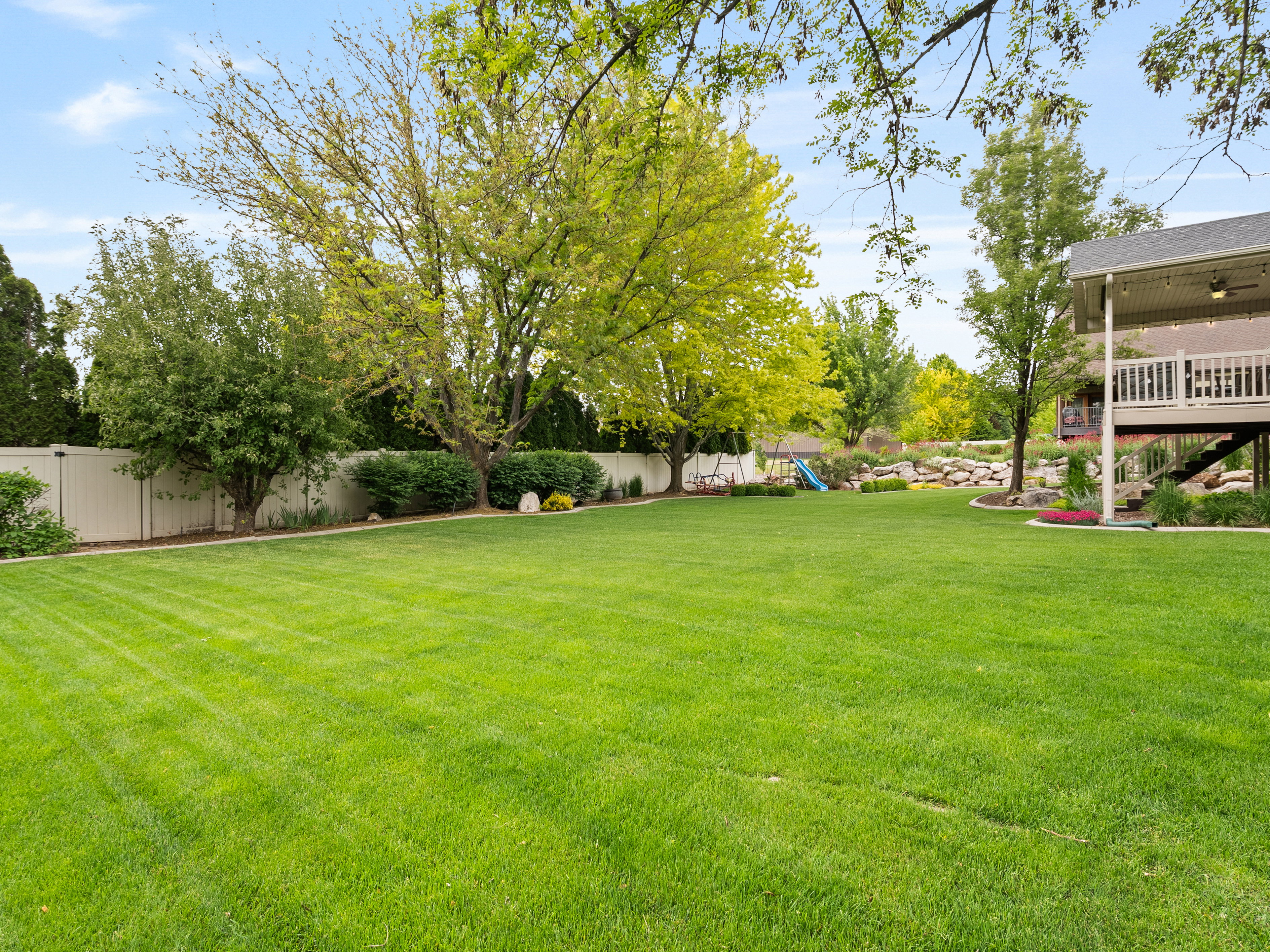 Expansive green lawn surrounded by mature trees and shrubs