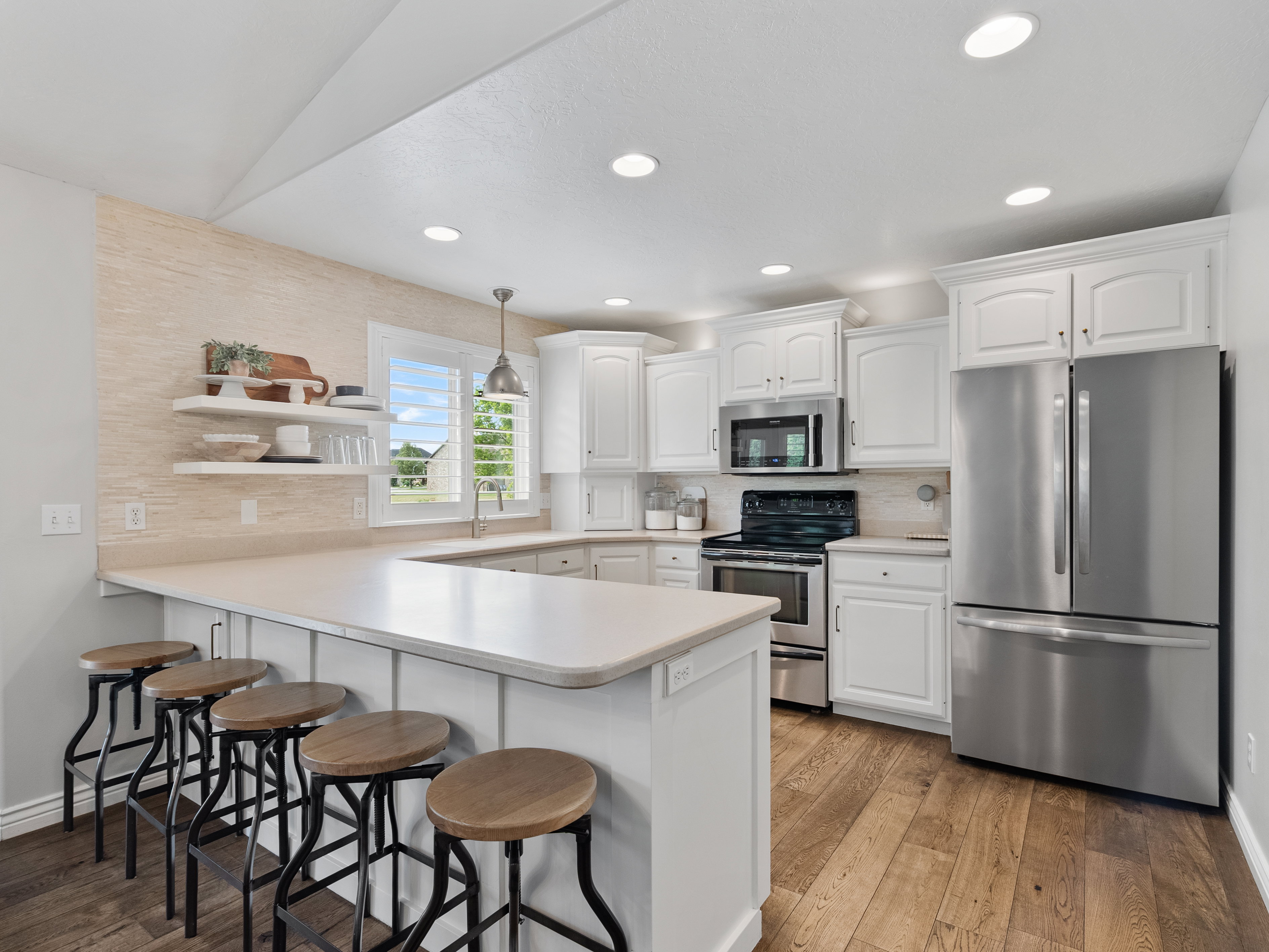 Contemporary kitchen featuring white cabinetry, stainless steel appliances, recessed lighting, and wood-finish flooring