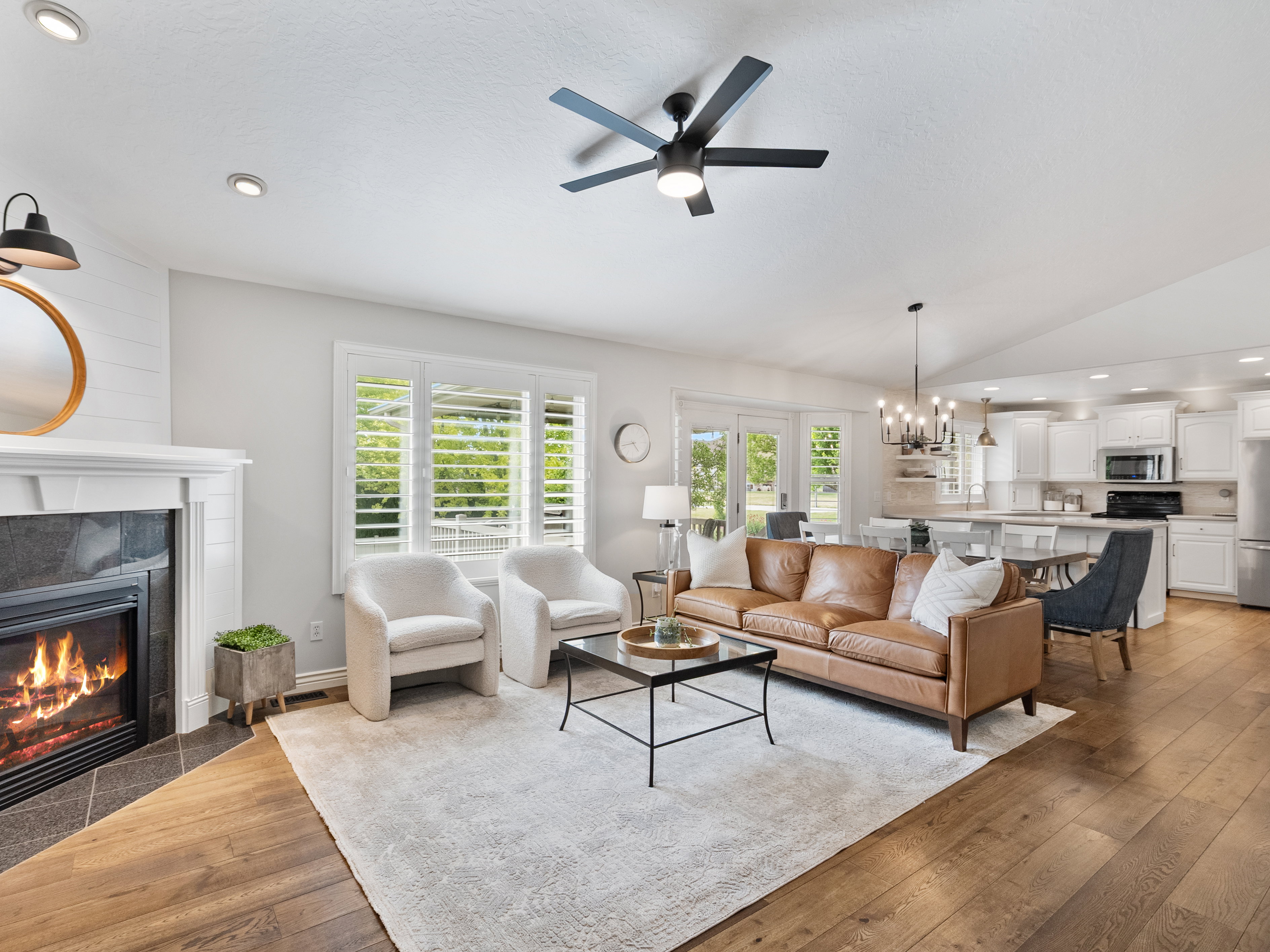 Open-concept living space featuring wood-finish flooring, a fireplace with dark tile surround and white mantel, and recessed lighting