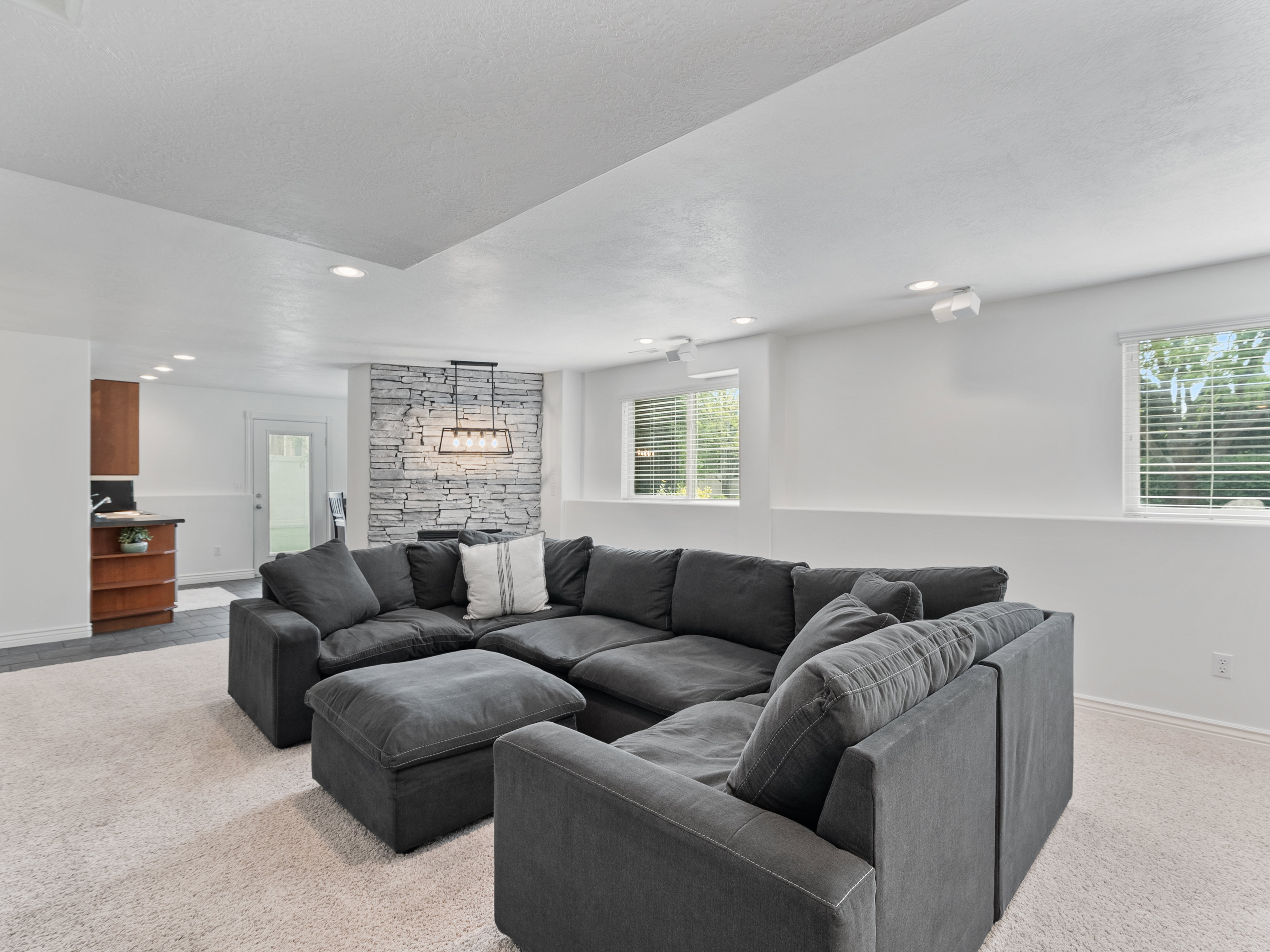 Spacious living area featuring light-toned carpeting and recessed lighting