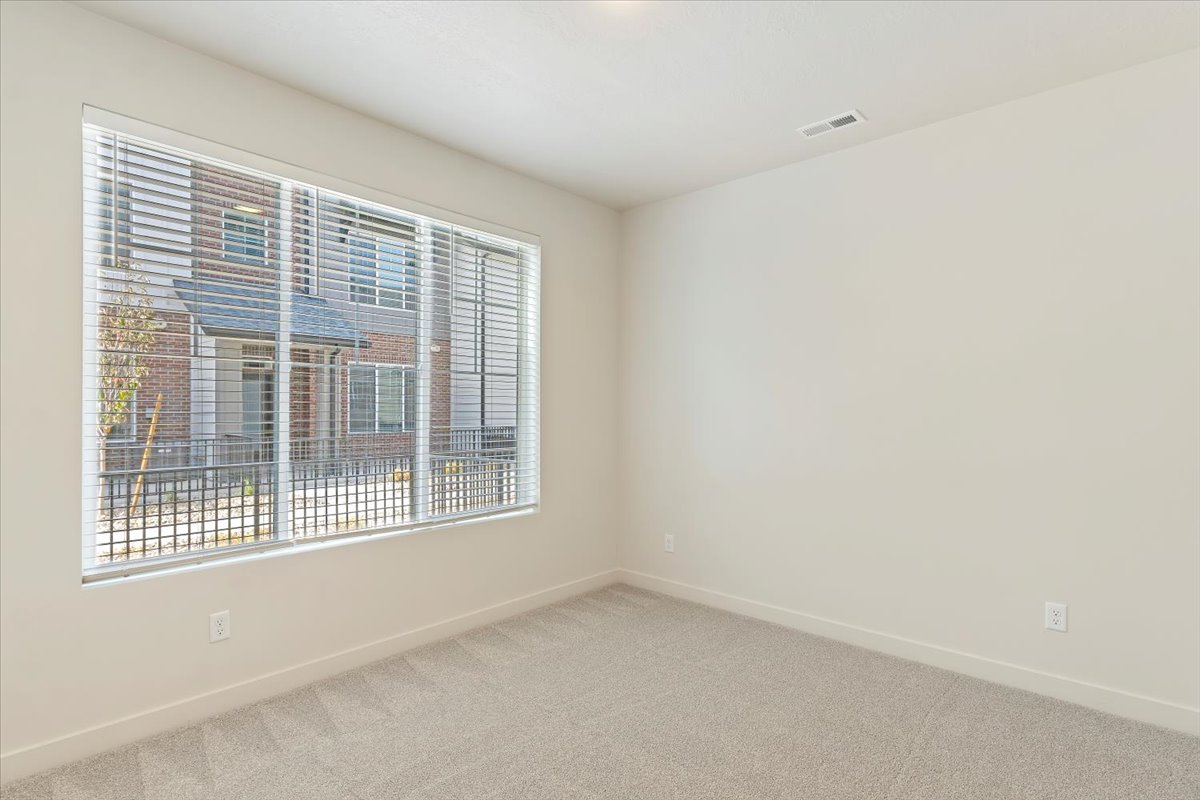 Bright room featuring a large window with horizontal blinds, neutral wall paint, and gray carpet flooring