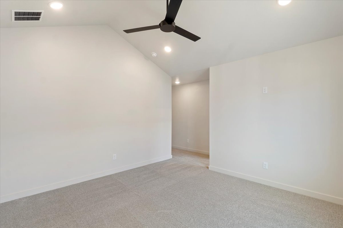 Spacious room featuring vaulted ceilings, recessed lighting, a ceiling fan, light gray carpeting, and white baseboards