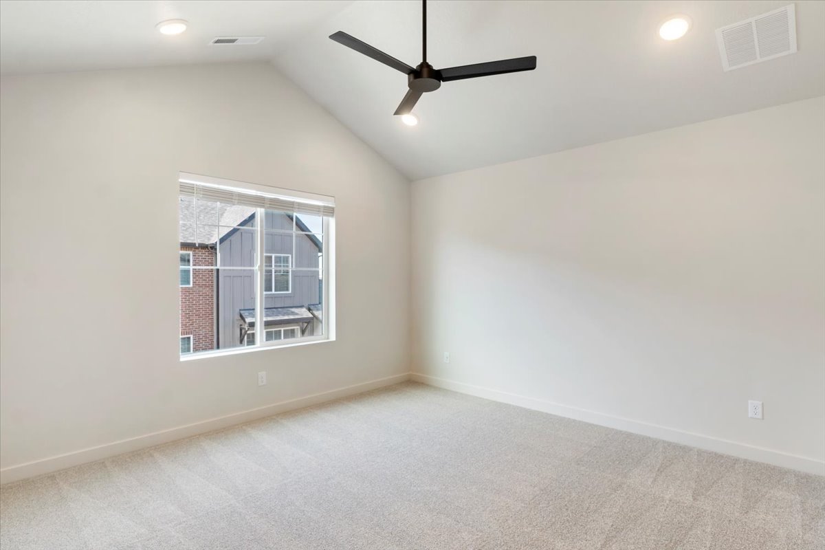 Vaulted ceiling bedroom featuring a large window, recessed lighting, ceiling fan, and light-toned carpet
