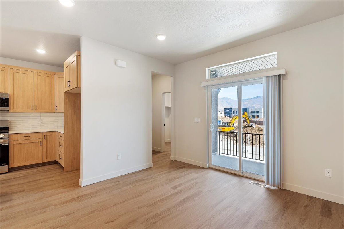 Contemporary living space featuring wood-finish flooring, recessed lighting, and a sliding glass door leading to a balcony