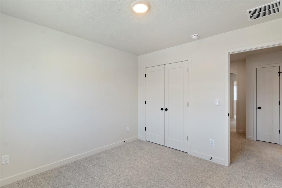 Interior room featuring light-toned carpeting, neutral wall paint, and white trim