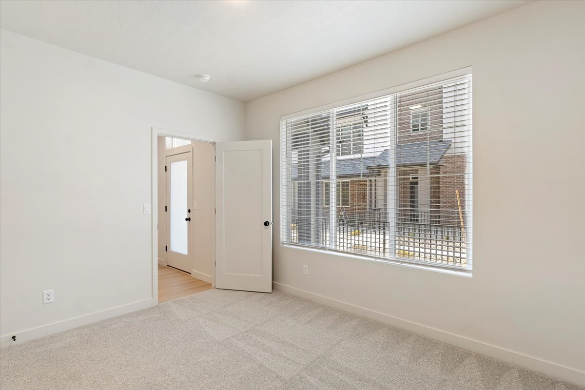 Carpeted room featuring large windows with horizontal blinds, providing natural illumination