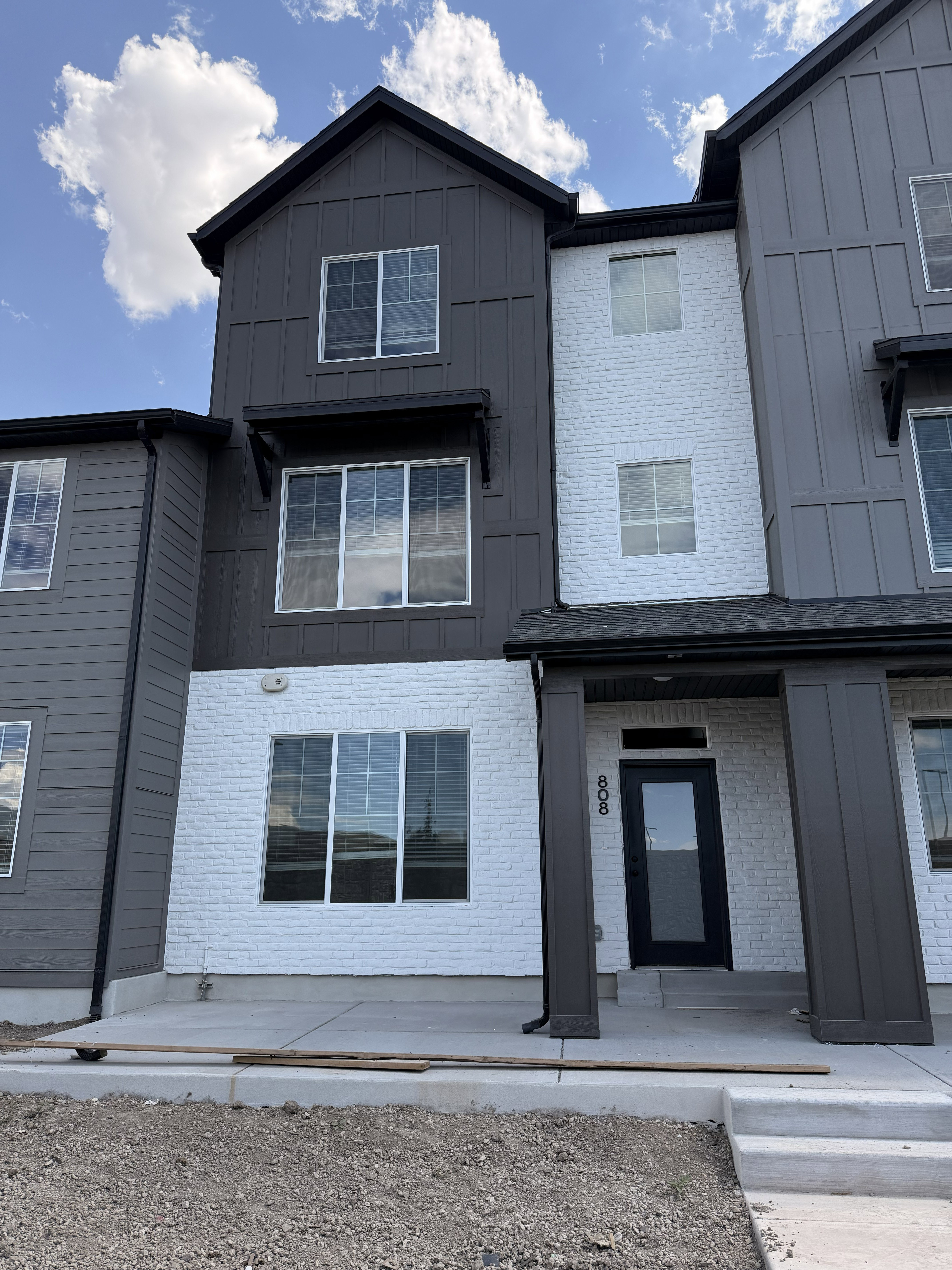 Contemporary multi-level exterior featuring dark gray vertical siding and white brick accents