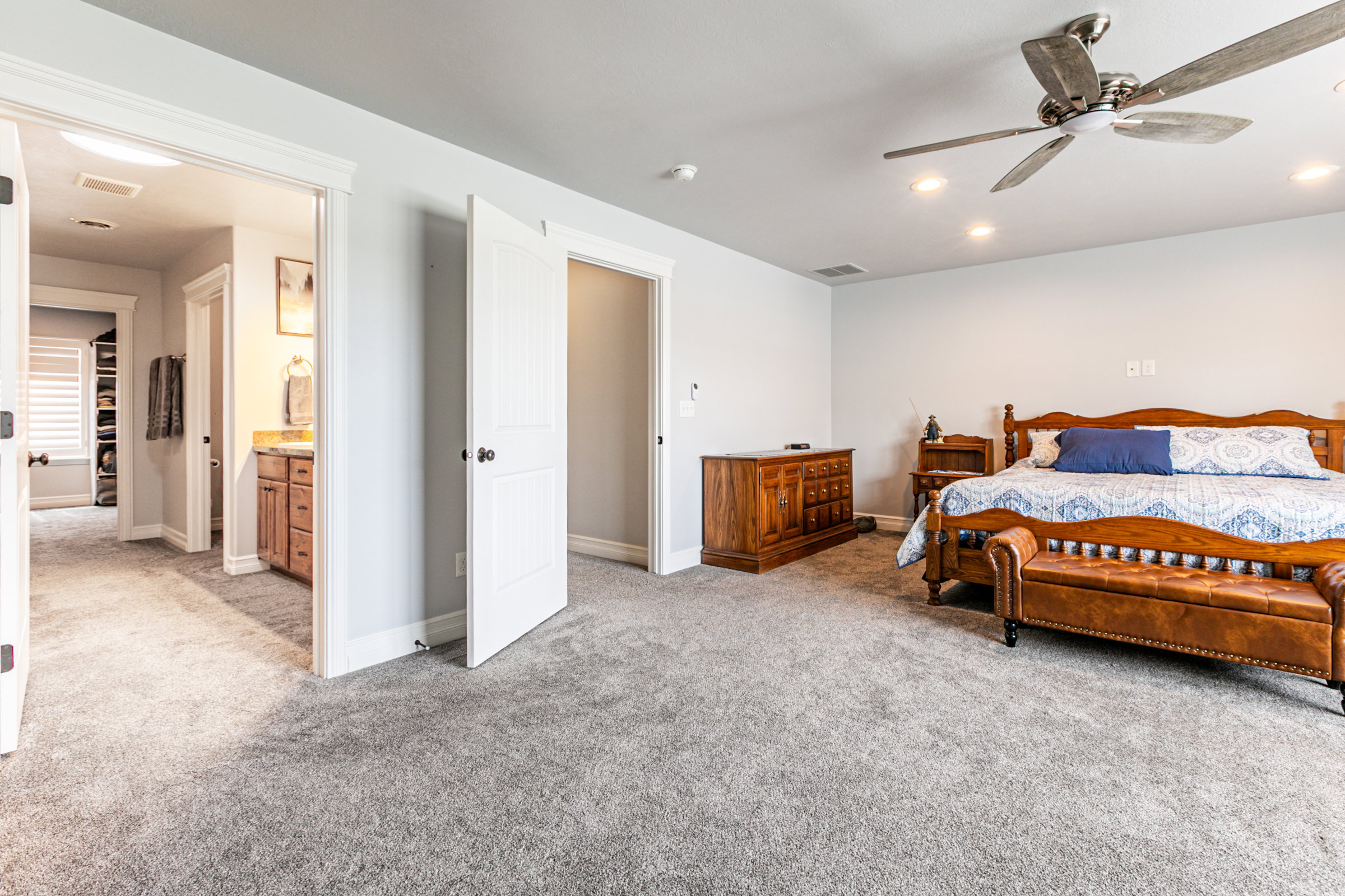 Spacious bedroom featuring plush gray carpeting, recessed lighting, and a ceiling fan