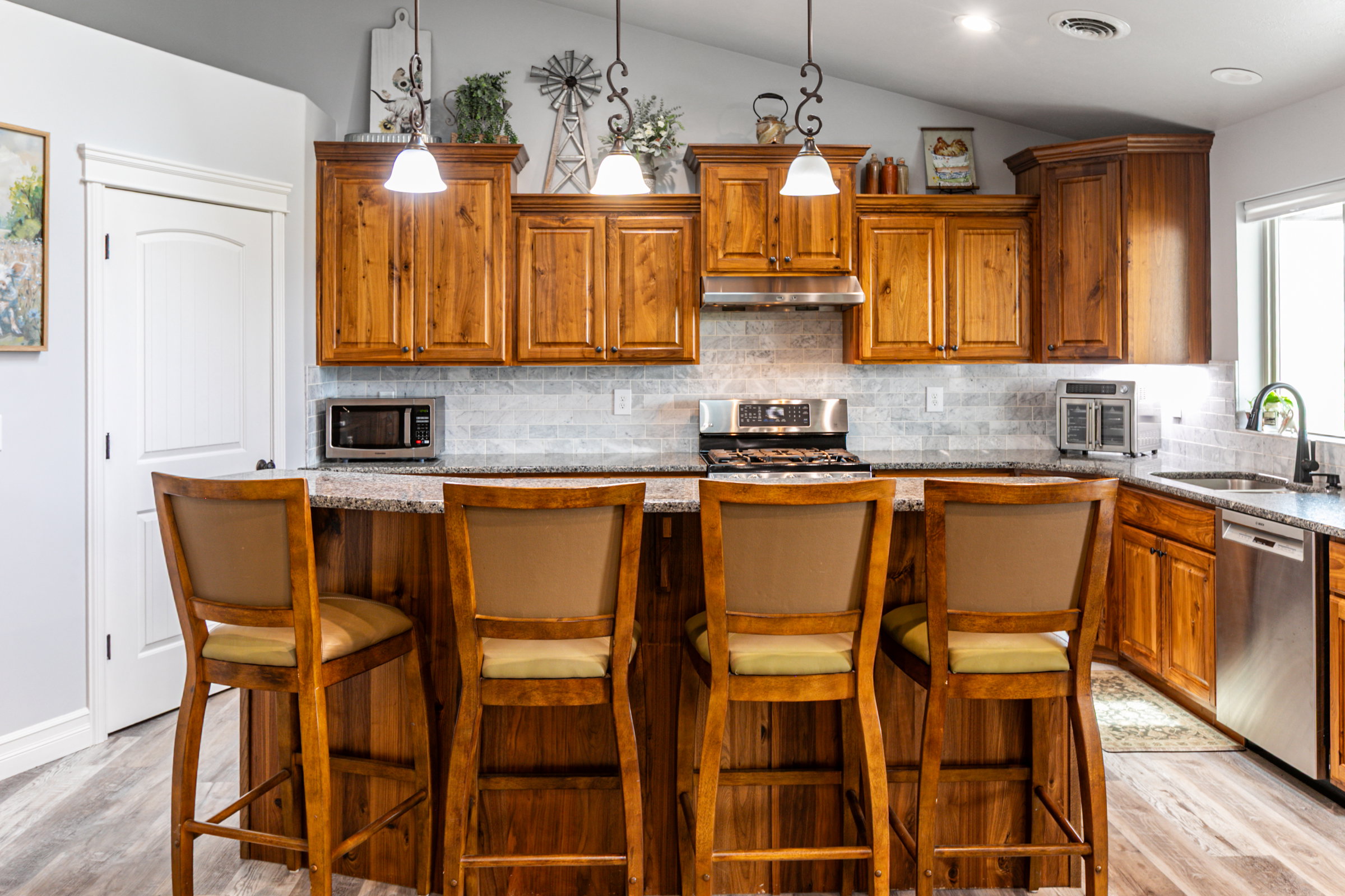 Kitchen featuring a central island with bar seating, wood cabinetry, granite-style countertops, and a tile backsplash