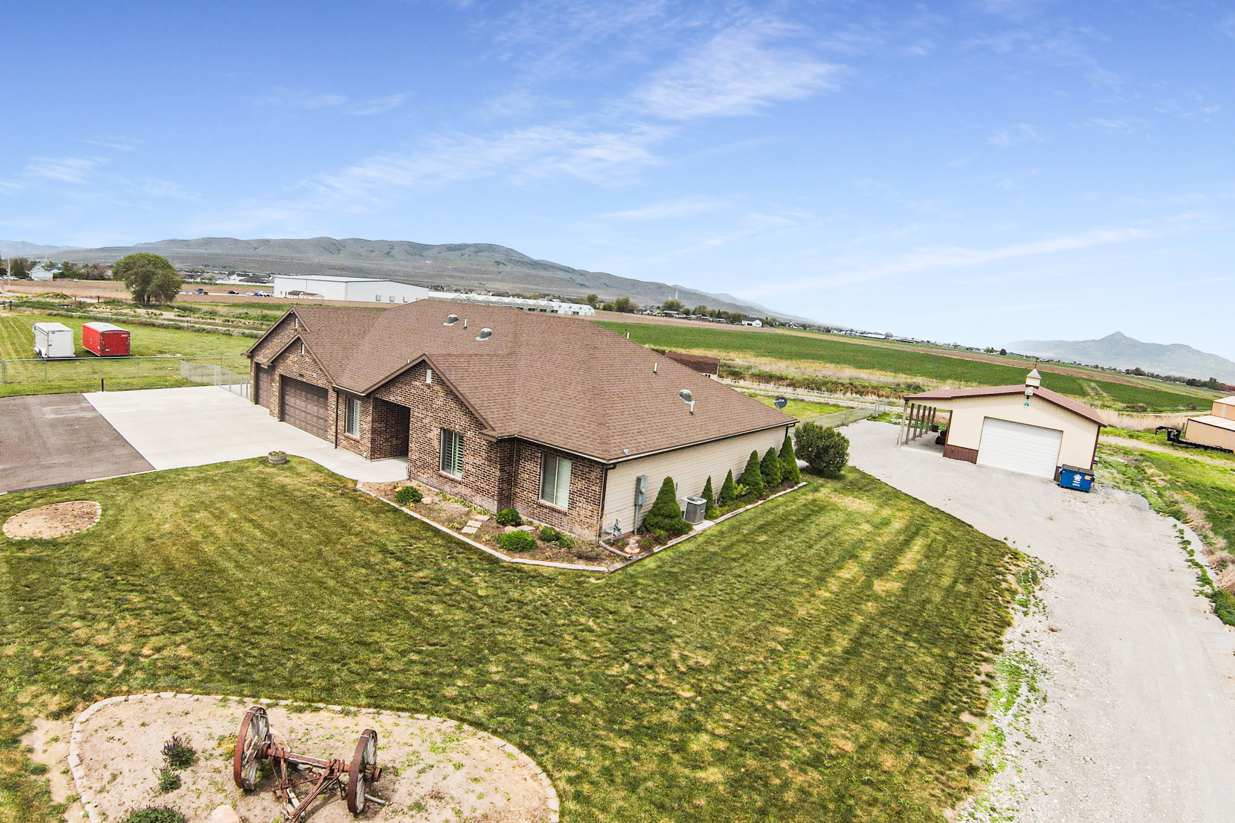 Brick-front residence featuring a multi-car garage with individual doors, a large concrete driveway, and established landscaping