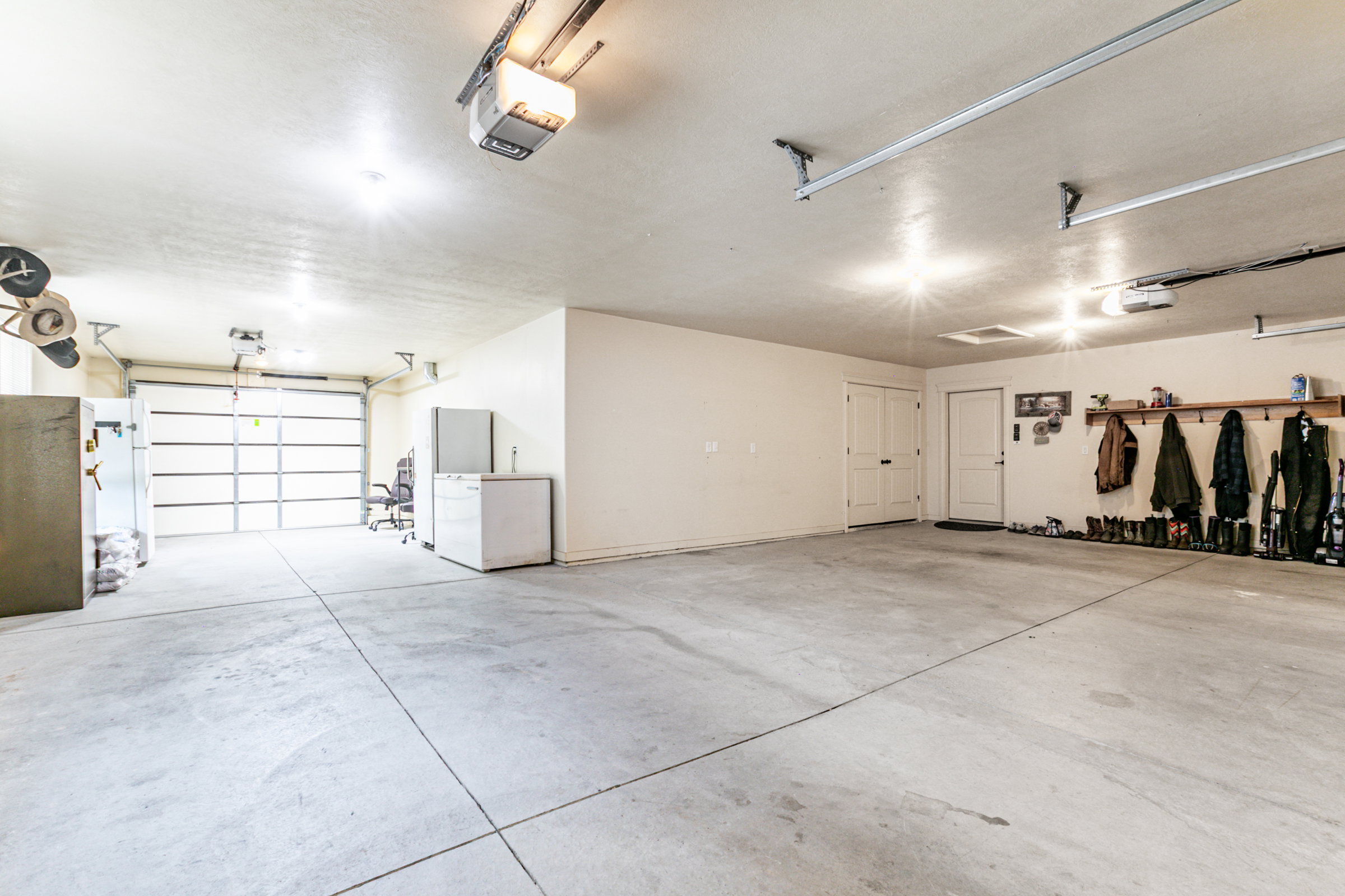 Spacious garage featuring a concrete floor, two overhead garage doors, two entry doors, and overhead lighting