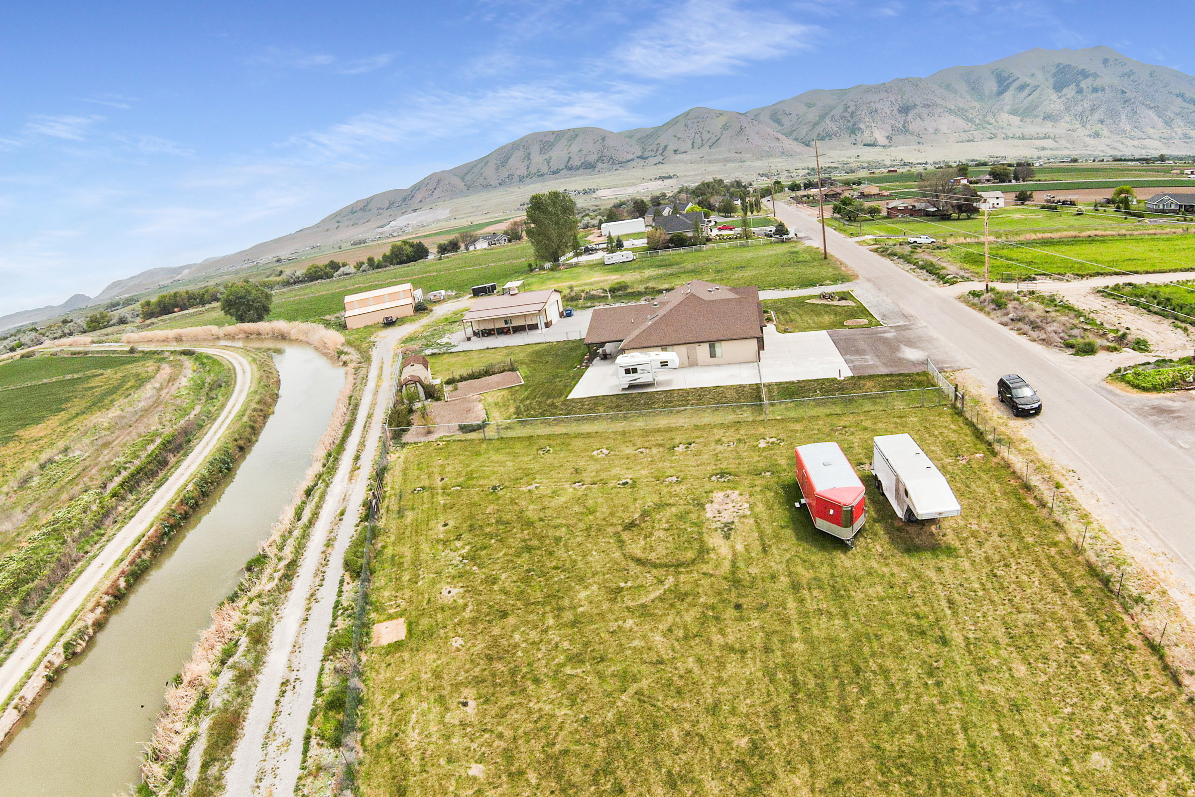 Expansive property featuring a brown-roofed residence, extensive paved driveway, and large grassy areas