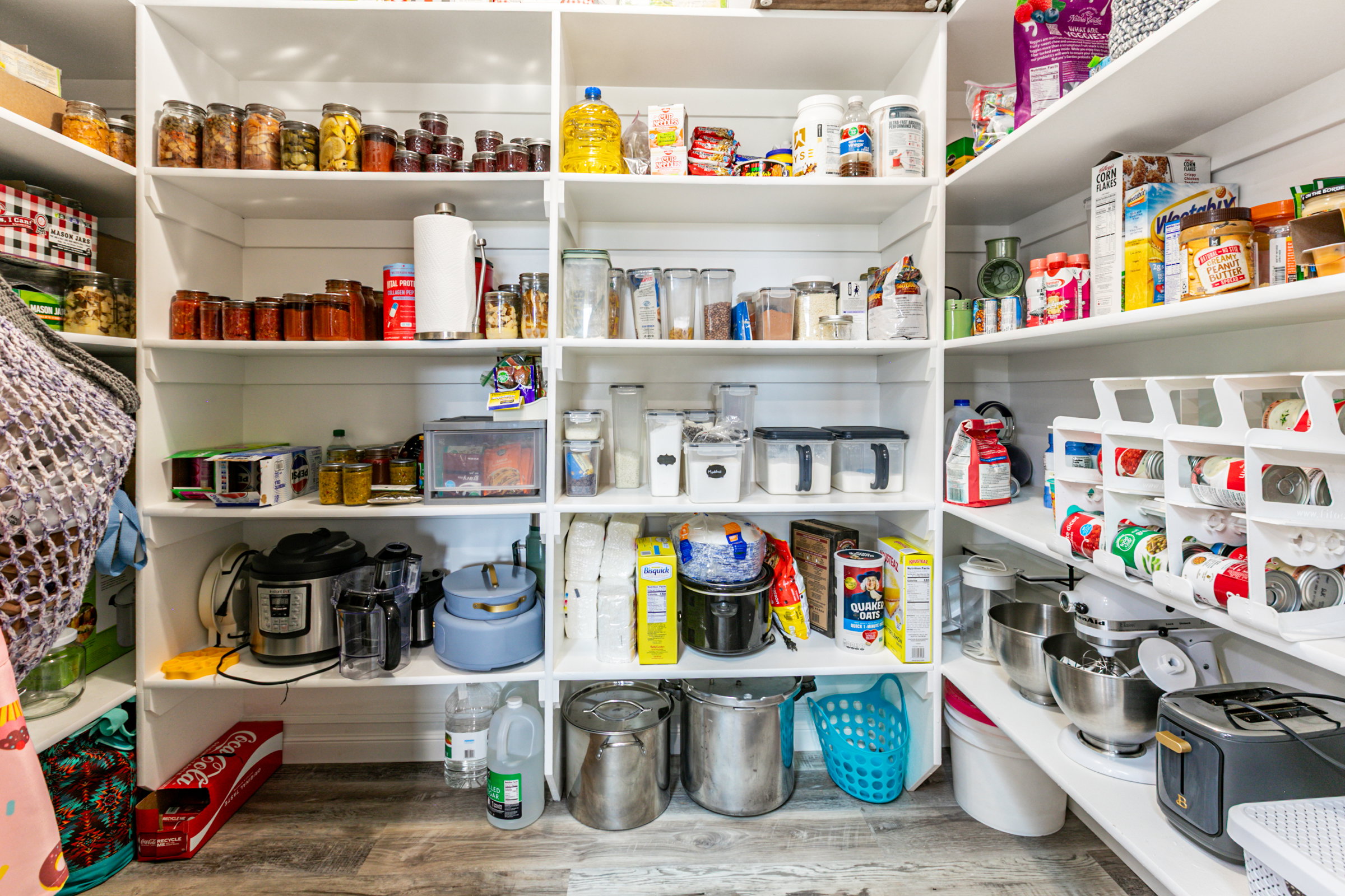 Expansive pantry featuring multi-level open shelving, shiplap wall finishes, and wood-finish flooring