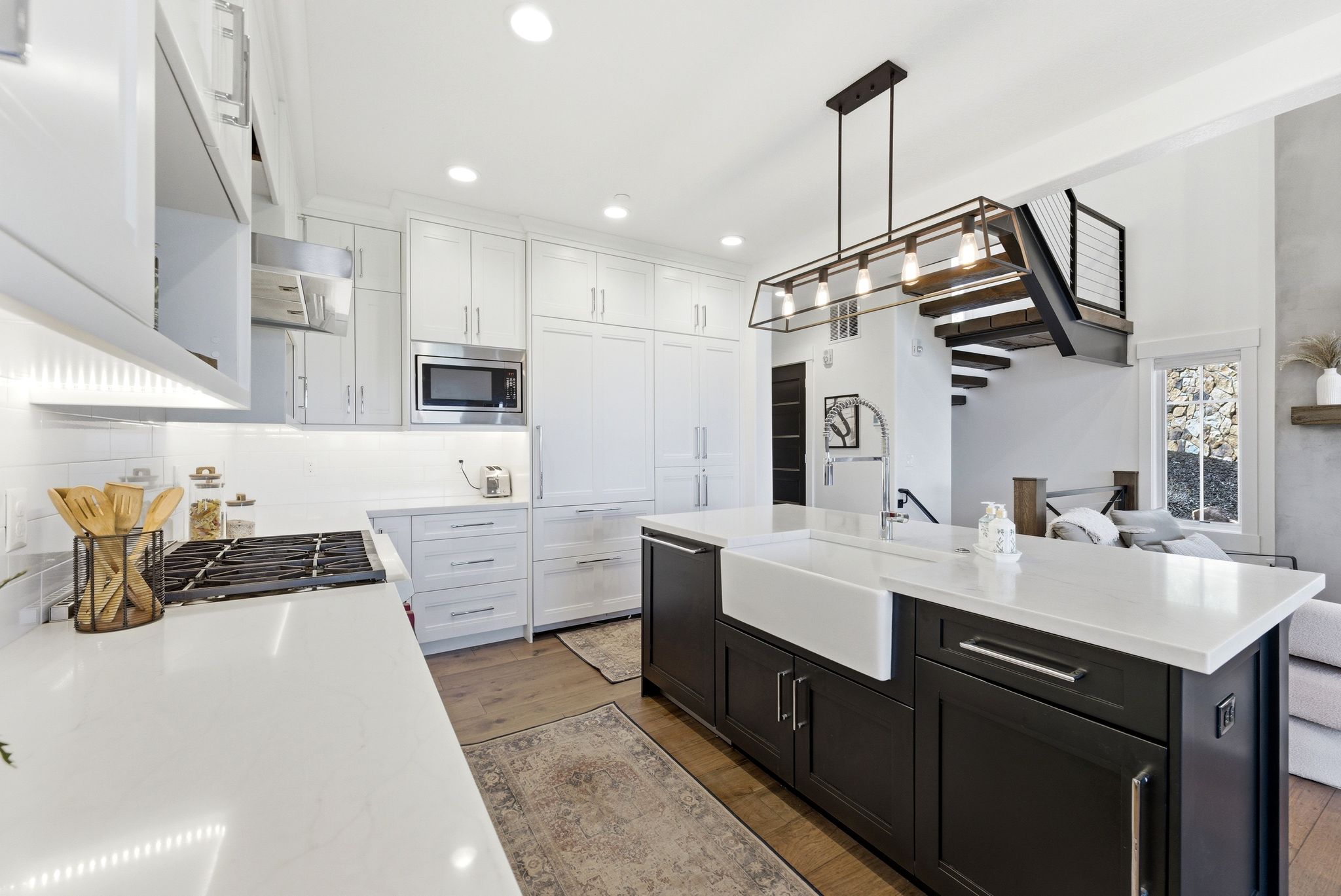 Modern kitchen featuring white cabinetry, stainless steel appliances, a gas range, and a large central island with a farmhouse sink