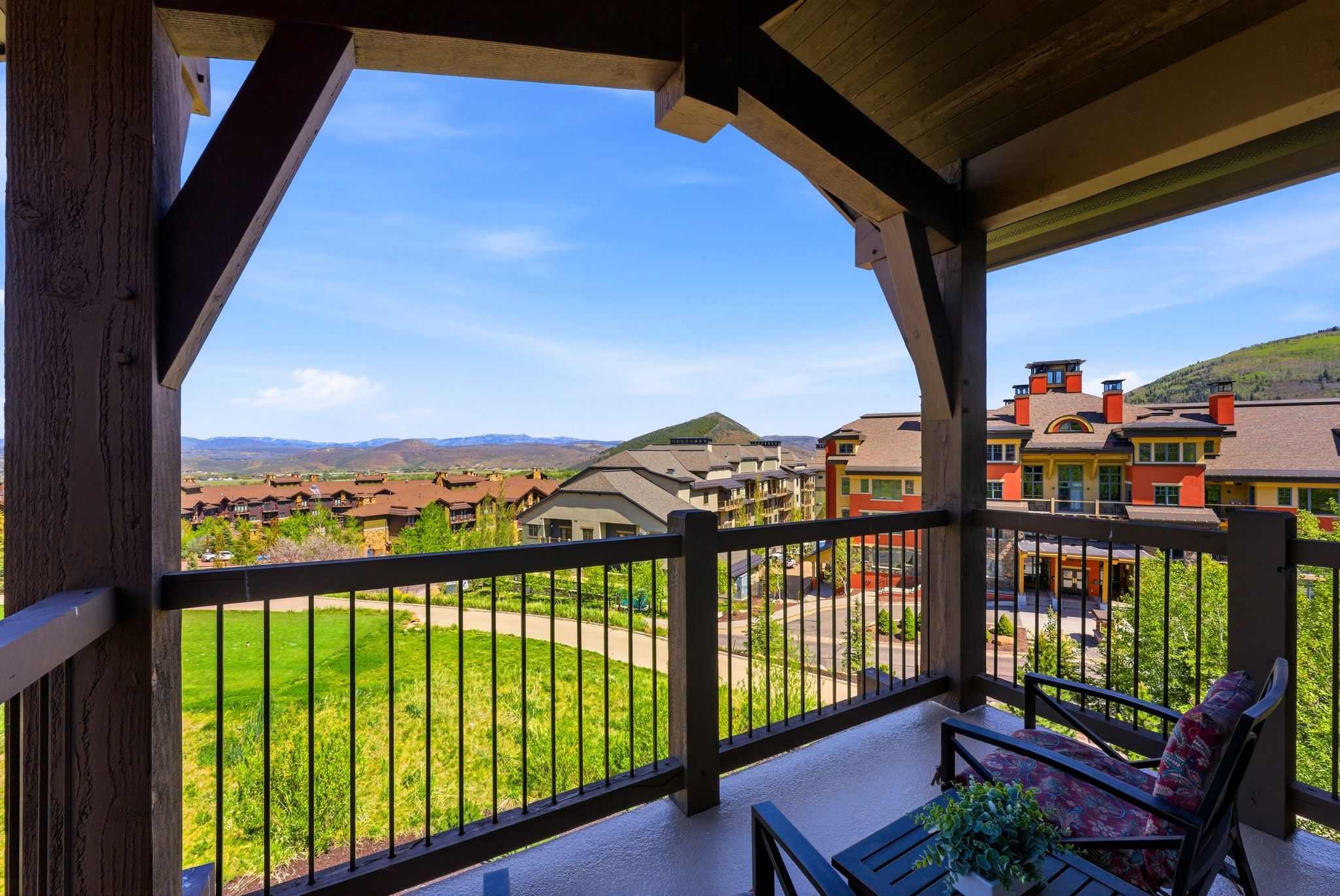 Expansive outdoor balcony featuring a robust wood-beam framework, dark wood railings with vertical metal balusters, and a concrete surface