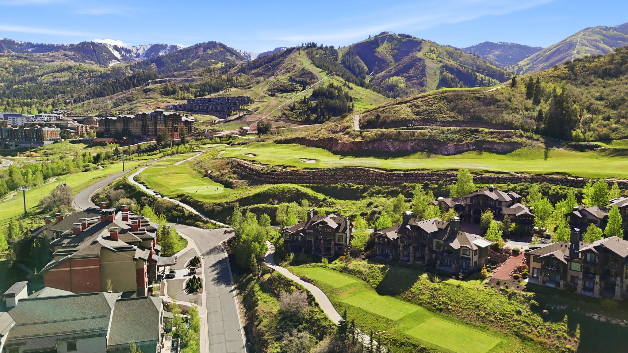 Aerial perspective showcasing properties set against a golf course and mountainous terrain