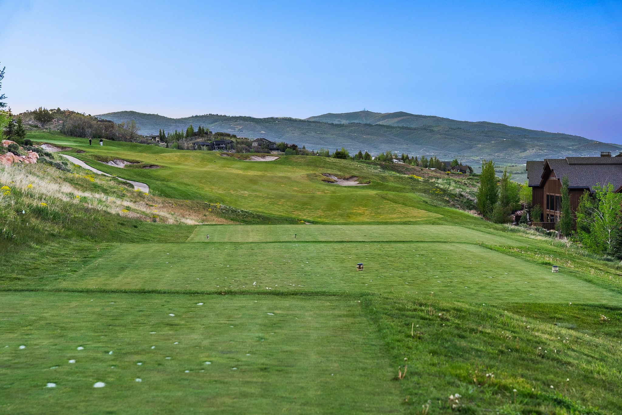 Expansive golf course setting featuring manicured green fairways and distant mountainous terrain