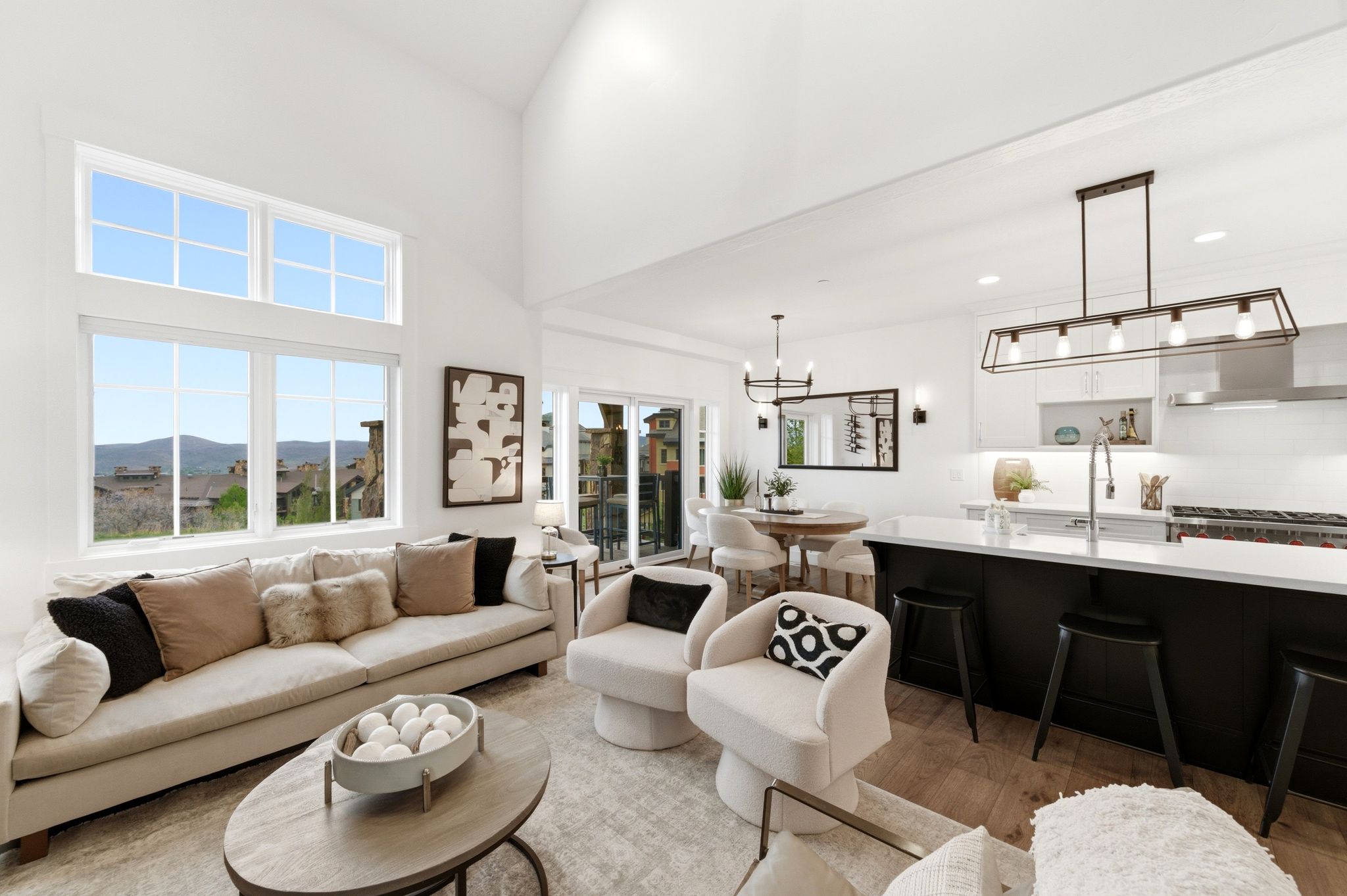 Open-concept living space featuring high ceilings, wood-finish flooring, a large kitchen island with seating, a range with hood, and a dining area