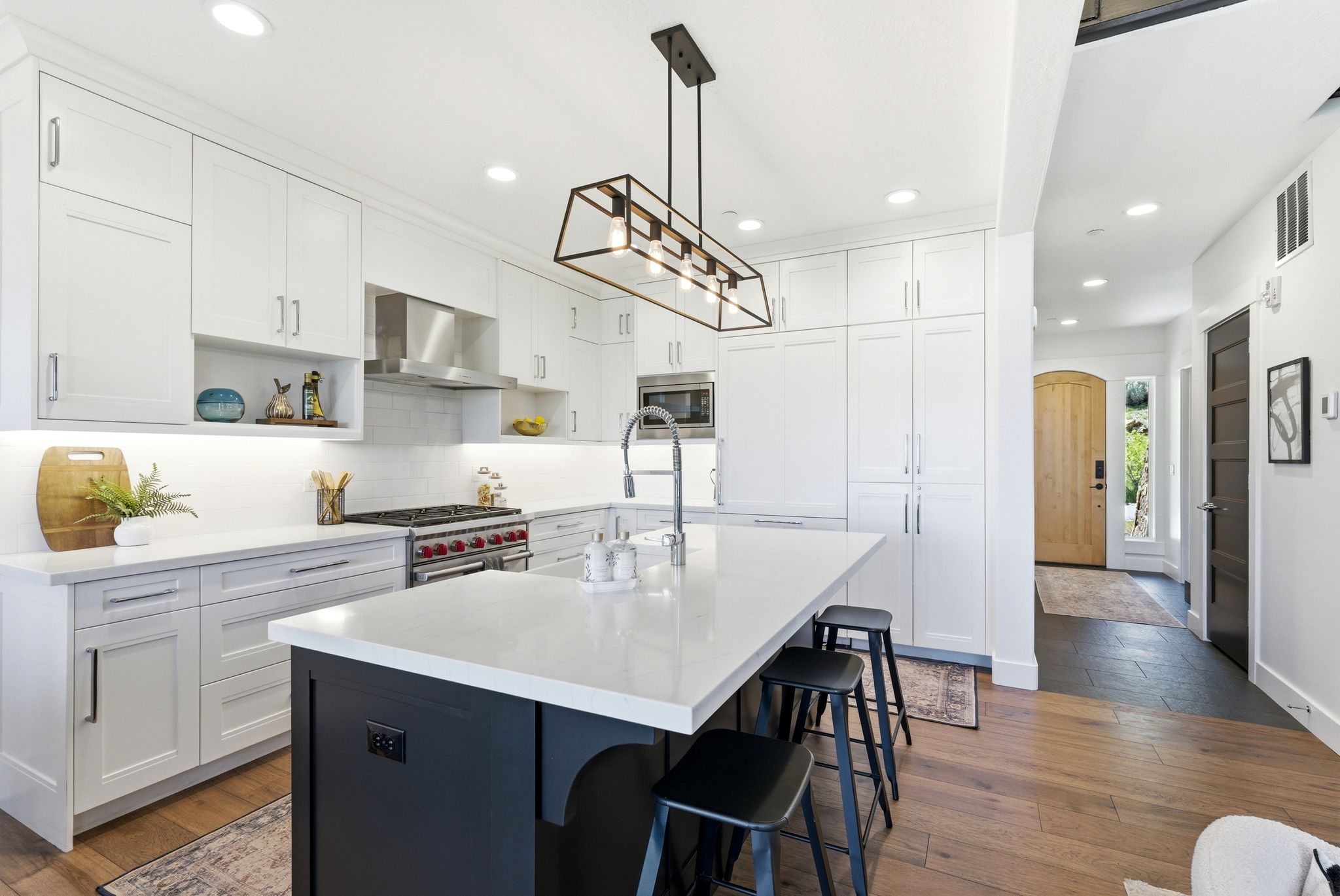 Modern kitchen featuring white cabinetry, a large center island with seating, stainless steel appliances, wood-finish flooring, and recessed lighting