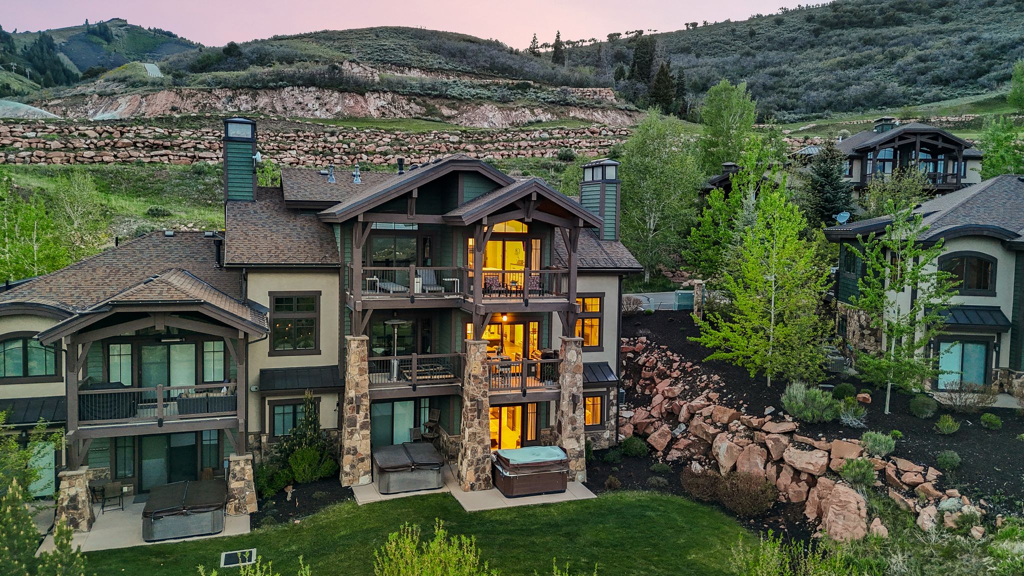 Multi-level property exterior with extensive balconies, stone column accents, and a manicured lawn