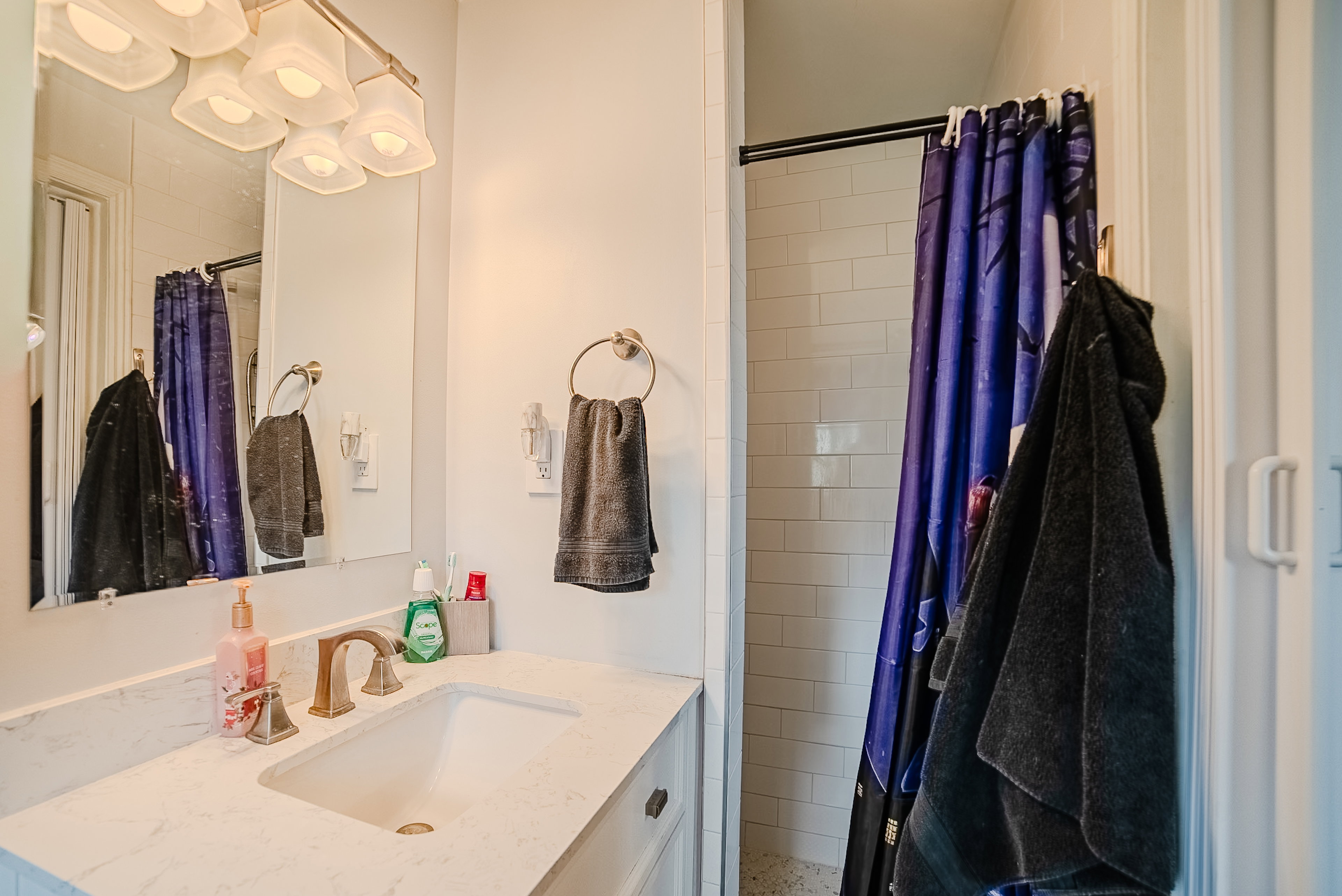 Bathroom vanity with a white countertop and rectangular undermount sink, complemented by a gold-toned faucet