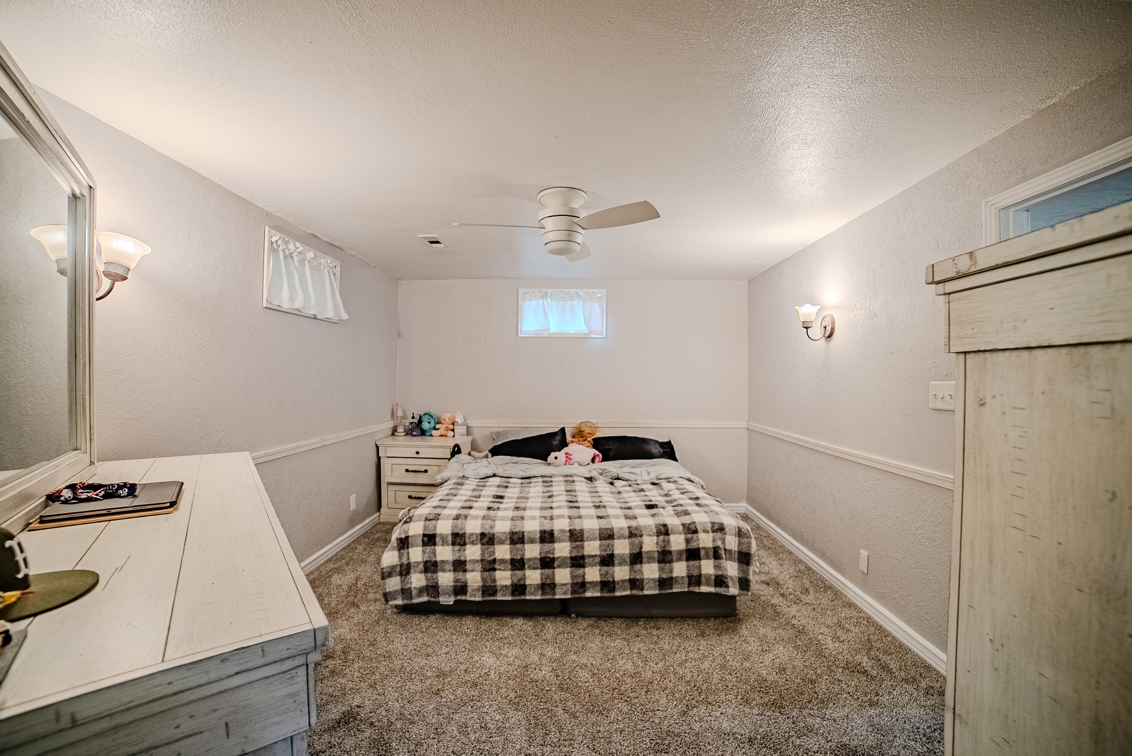 Carpeted bedroom with a ceiling fan, wall sconces, and chair rail molding