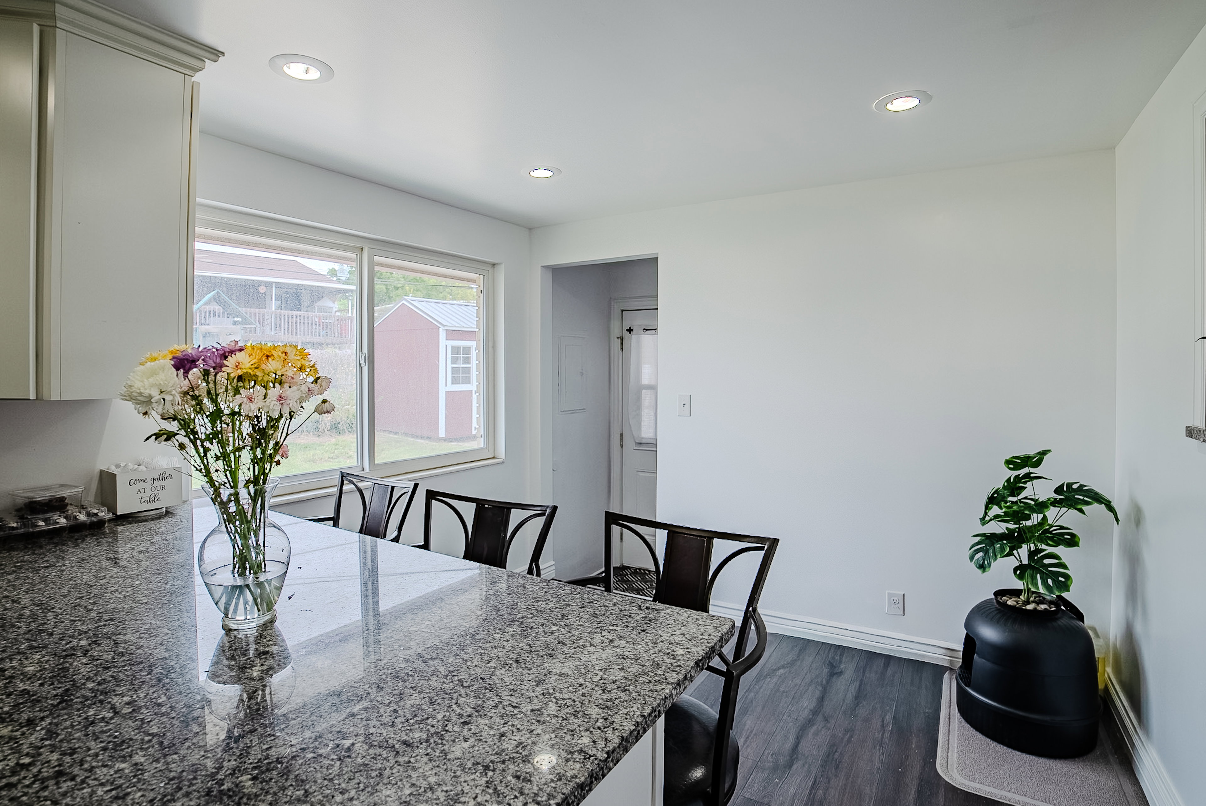Kitchen featuring a granite-finish countertop, white cabinetry with crown molding, recessed ceiling lighting, and wood-finish flooring