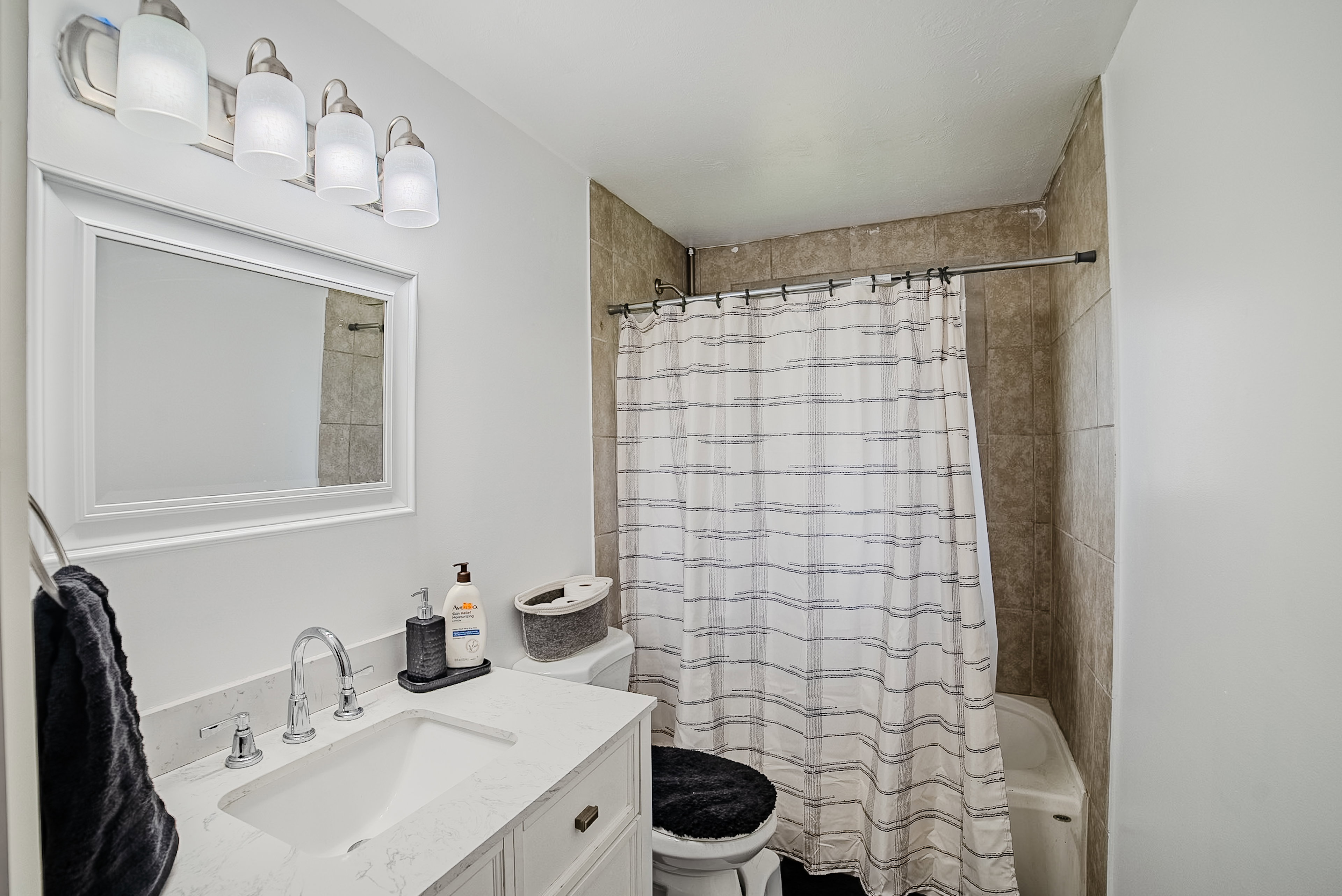 Bathroom featuring a white vanity with an integrated sink and chrome fixtures, a framed mirror, and a four-light fixture