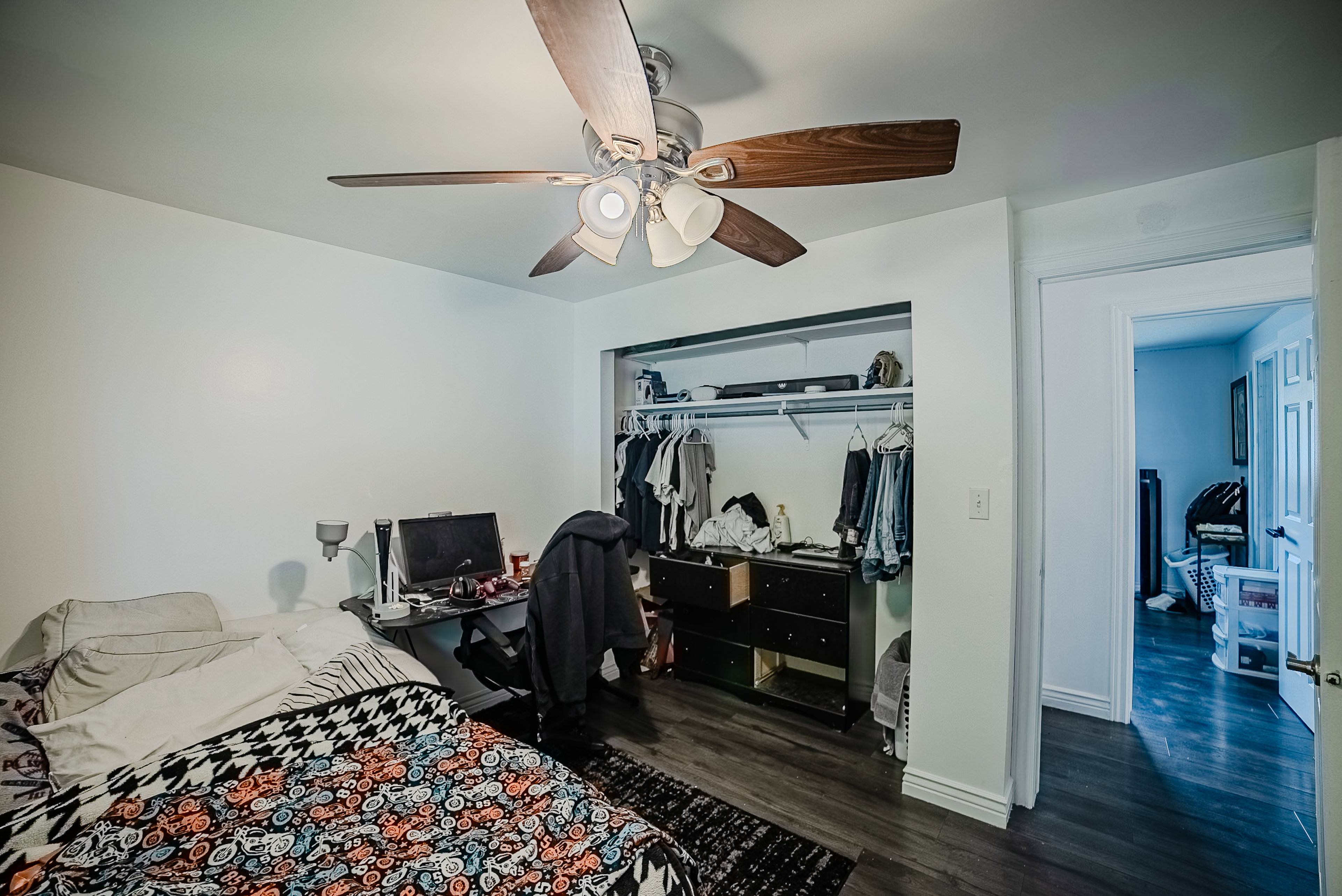 Bedroom featuring wood-finish flooring, white painted walls, and a ceiling fan with integrated lighting