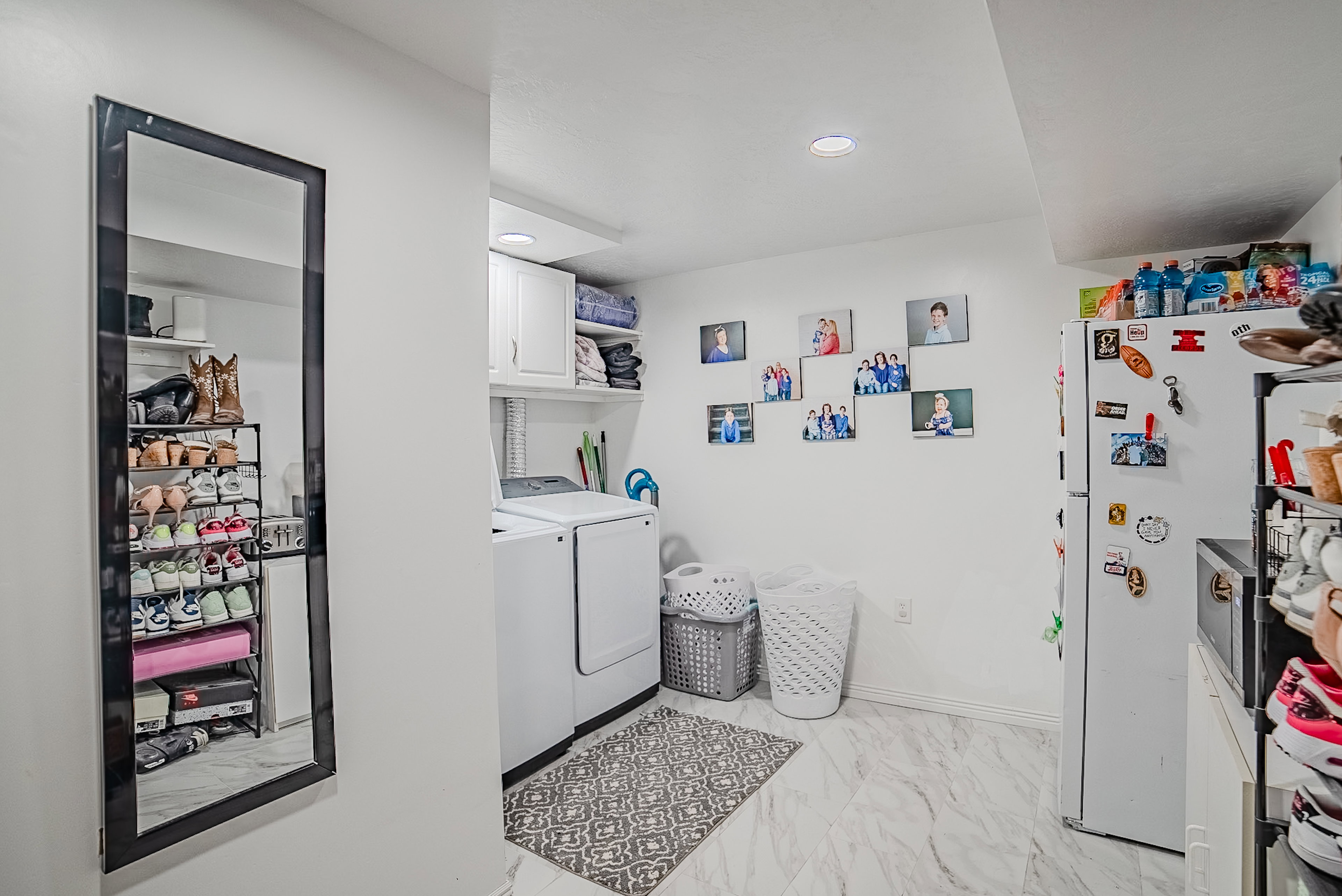Laundry area featuring white cabinetry, a built-in shelving unit, and marble-look flooring