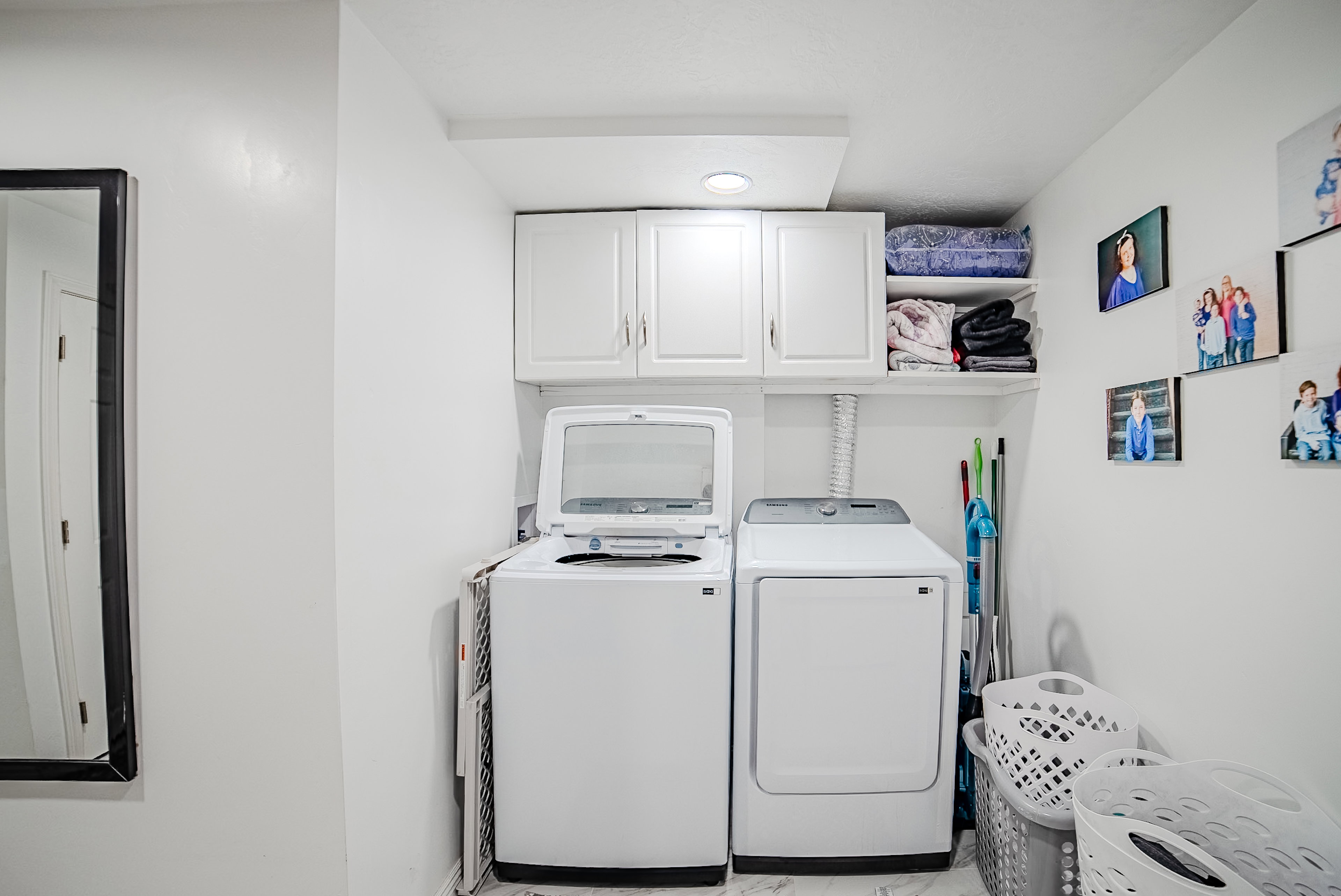 Dedicated laundry area featuring a washer and dryer, upper cabinetry, and open shelving
