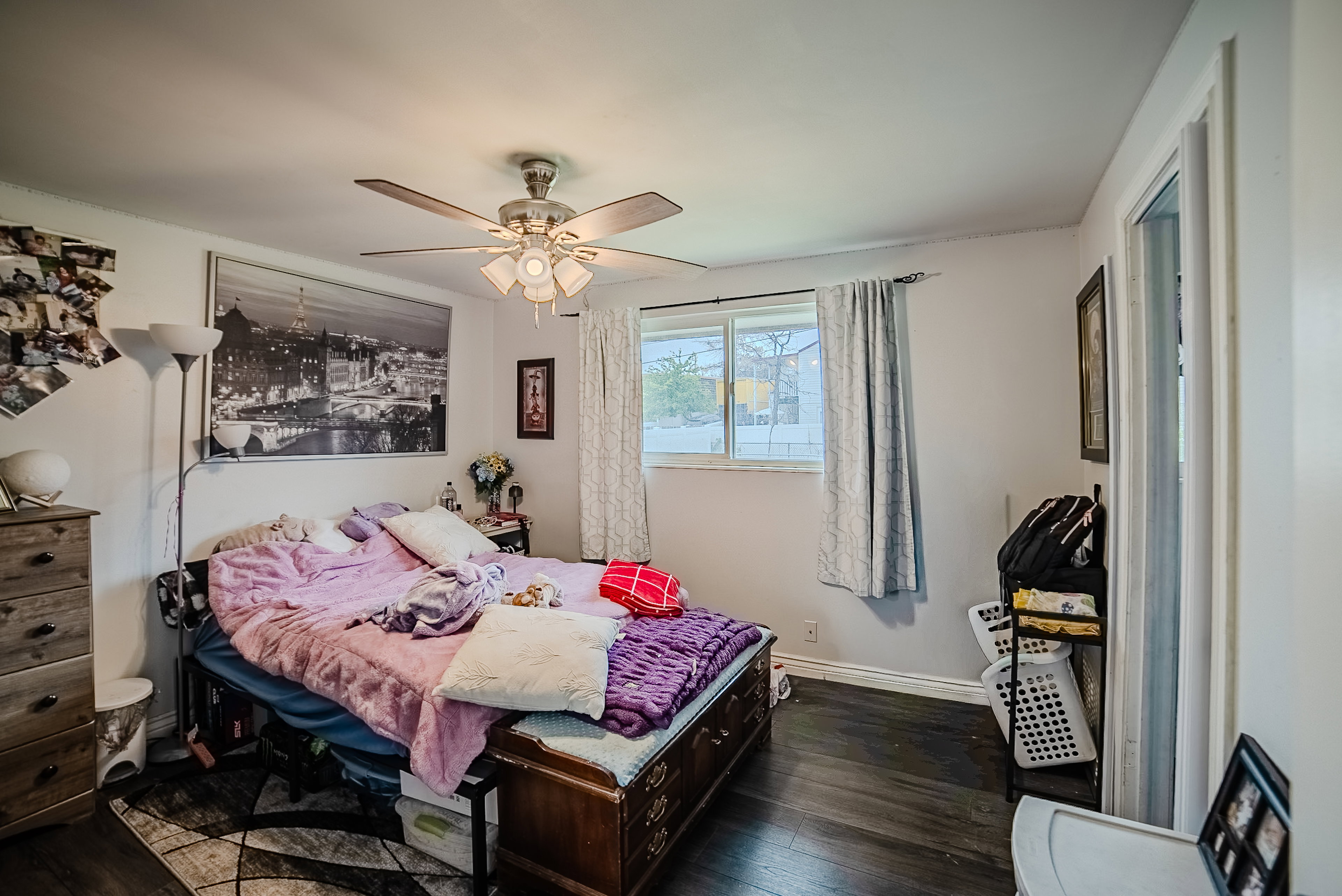 Bedroom featuring wood-finish flooring, a ceiling fan with integrated lighting, and a window with natural light