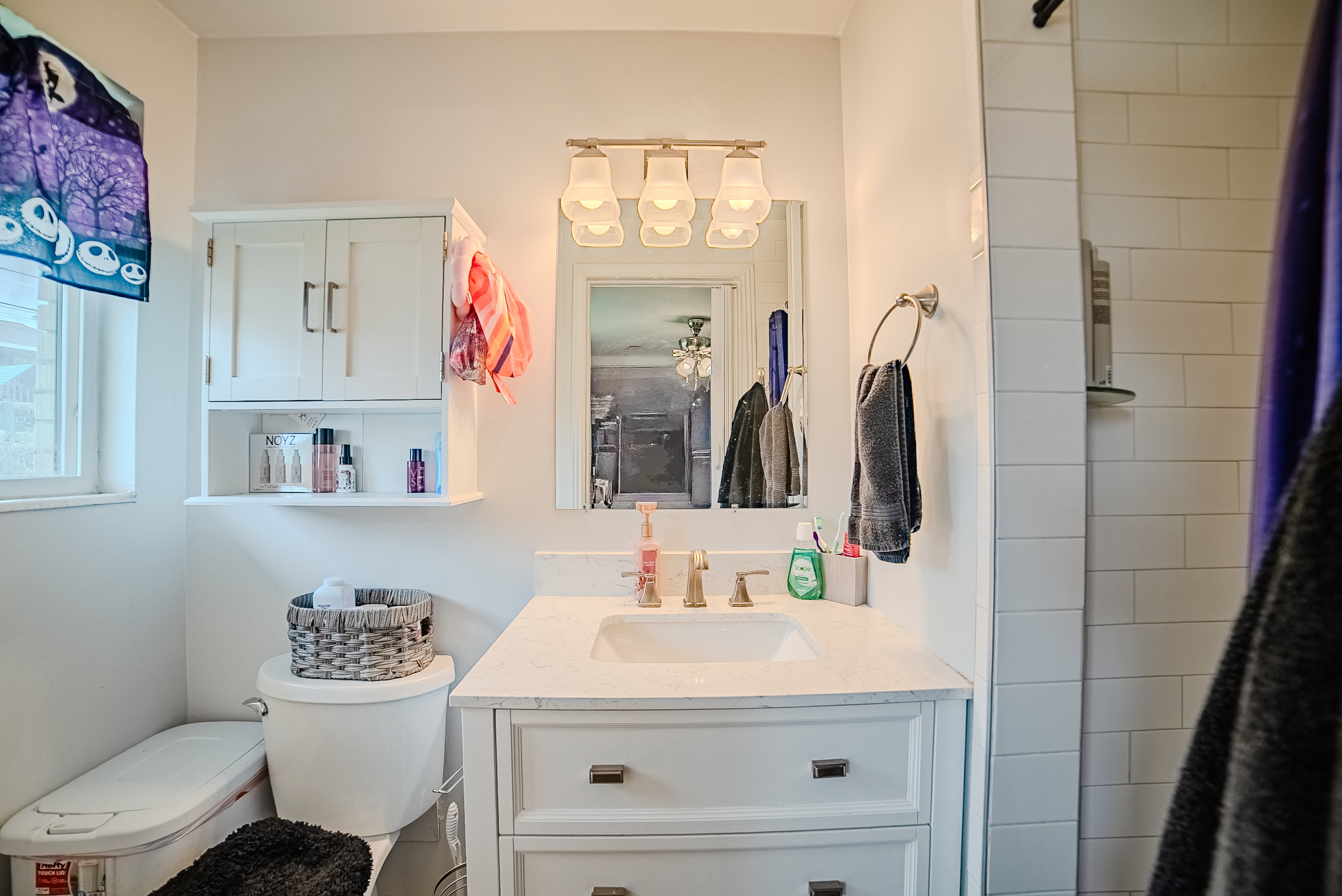 Bathroom featuring a single vanity with stone countertop, white shaker-style cabinetry, and a rectangular undermount sink