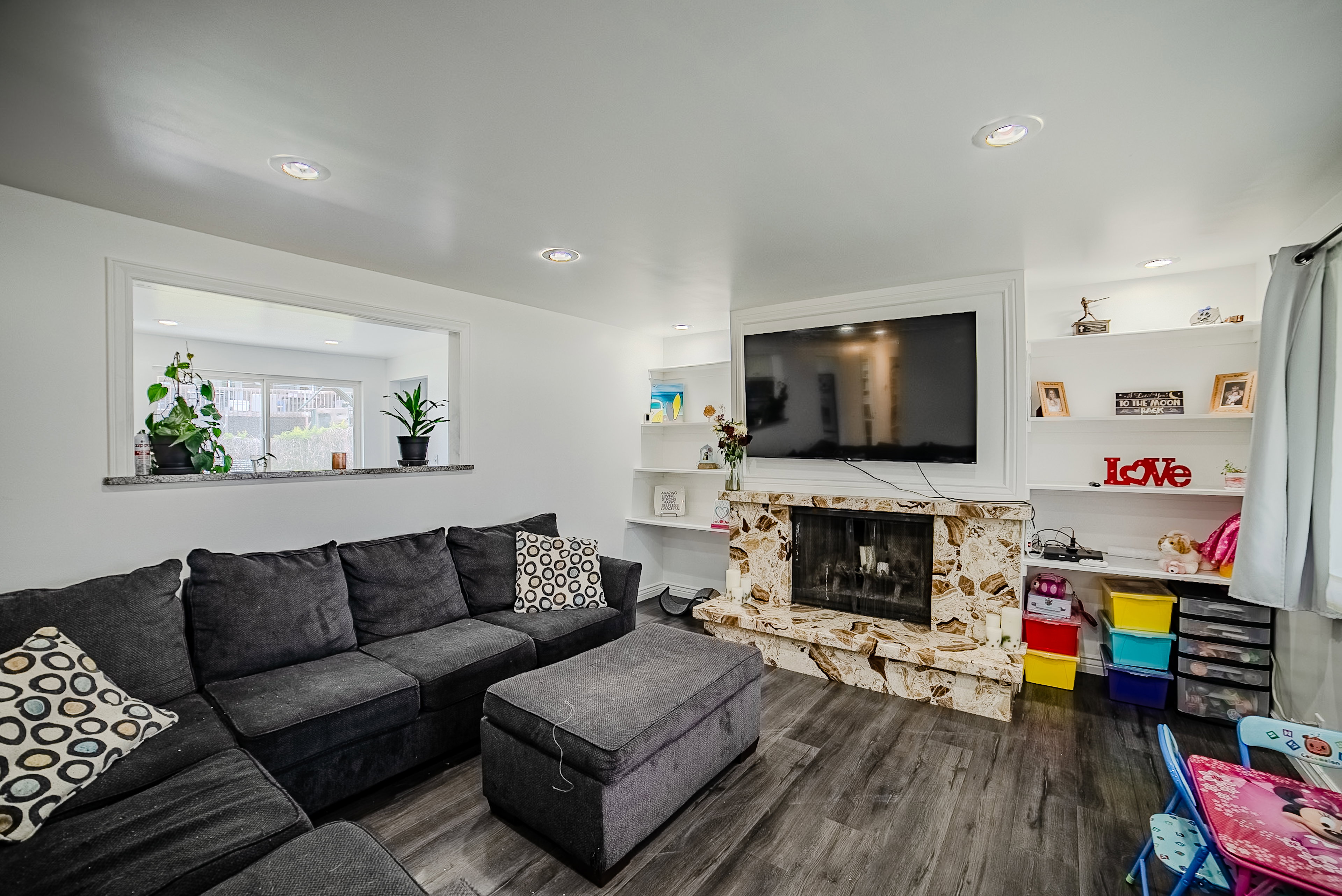 Living area featuring a stone-clad fireplace and wood-finish flooring