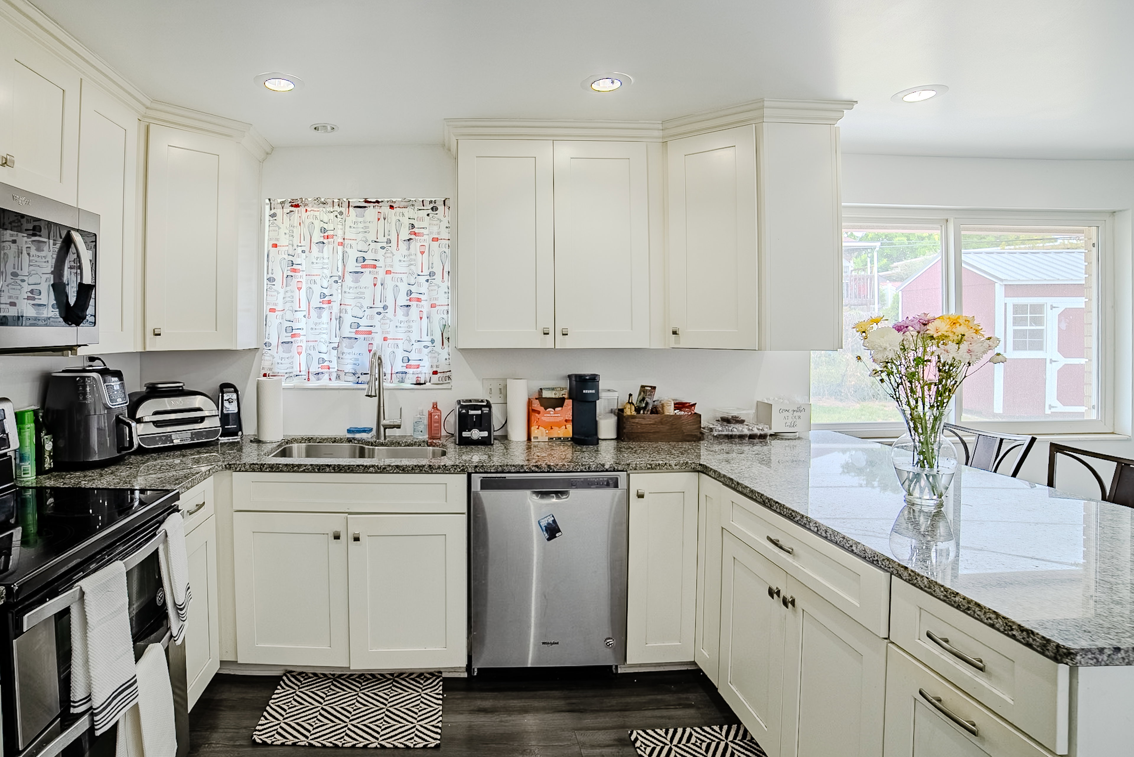 Kitchen featuring white cabinetry, granite countertops, stainless steel appliances, a stainless steel sink with a gooseneck faucet, and wood-finish flooring
