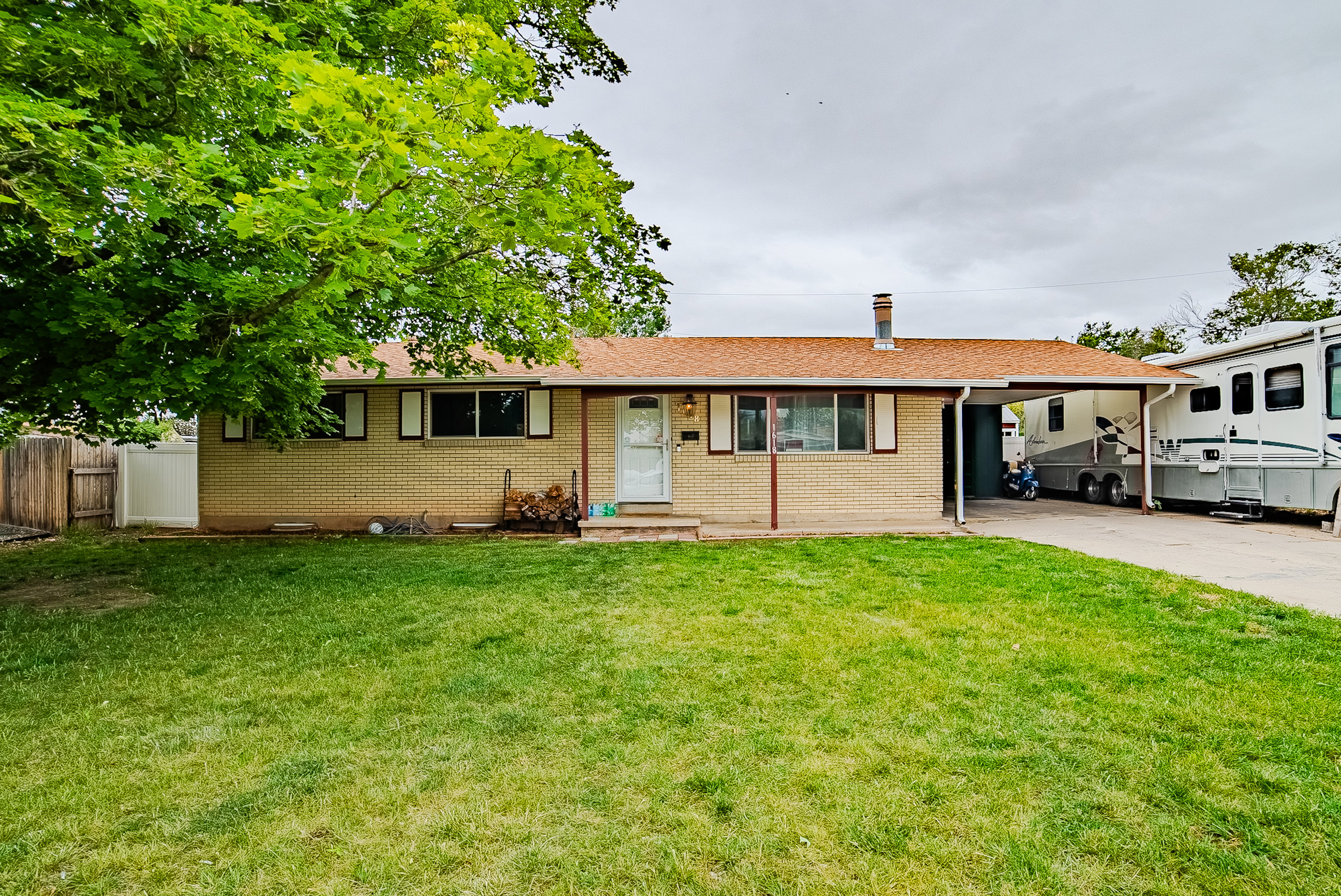 Ranch-style exterior with brick siding, a covered entry, and an attached carport