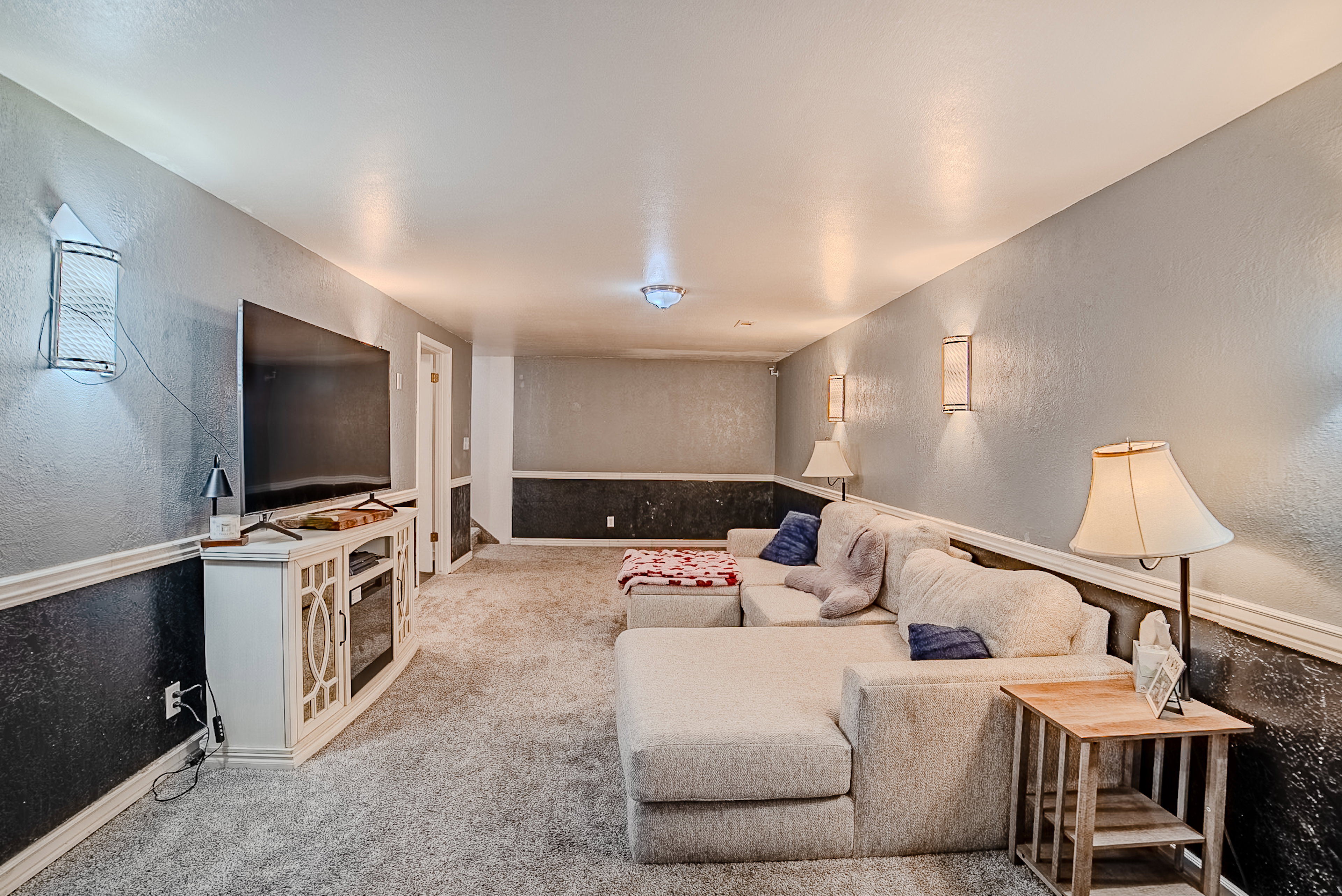 Carpeted recreation room featuring textured two-tone walls with chair rail molding