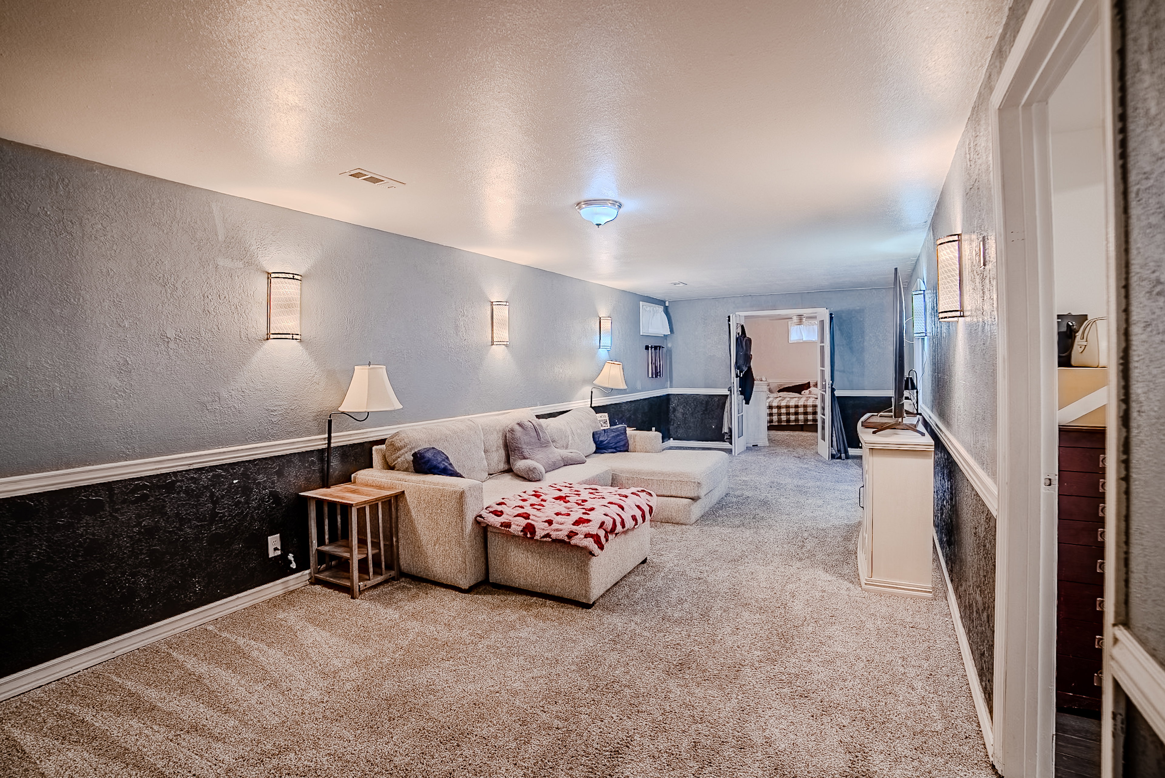 Spacious recreation room featuring textured walls, wainscoting, and recessed lighting