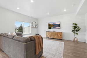 Spacious living area featuring light wood-finish flooring, recessed lighting, and a white shiplap accent wall