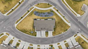 Aerial perspective of a cul-de-sac residence with a gray shingle roof, concrete driveways, and surrounding green space