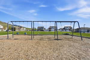 Community park with swing set on wood chip surfacing, bordered by green lawn