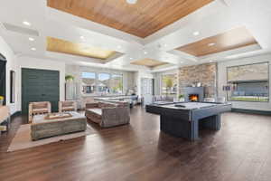 Spacious common area featuring wood-finish flooring, recessed lighting, and tray ceilings with wood panel accents