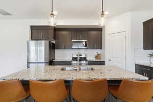 Kitchen featuring a large central island with a built-in sink and stone countertop