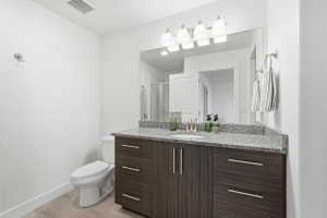 Bathroom featuring a wood-finish vanity with a granite countertop, undermount sink, and a large wall mirror