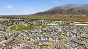 Expansive residential development featuring a diverse collection of single-family homes and townhomes, surrounded by open green spaces and a mountainous backdrop