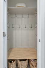 Built-in mudroom style storage featuring board and batten paneling, multiple coat hooks, an upper shelf, and a lower storage bench