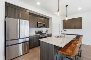 Modern kitchen featuring a large center island with integrated sink, light-toned countertop, and pendant lighting