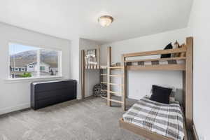 Bedroom 1. Light-filled room featuring a large window, neutral carpet, and white walls